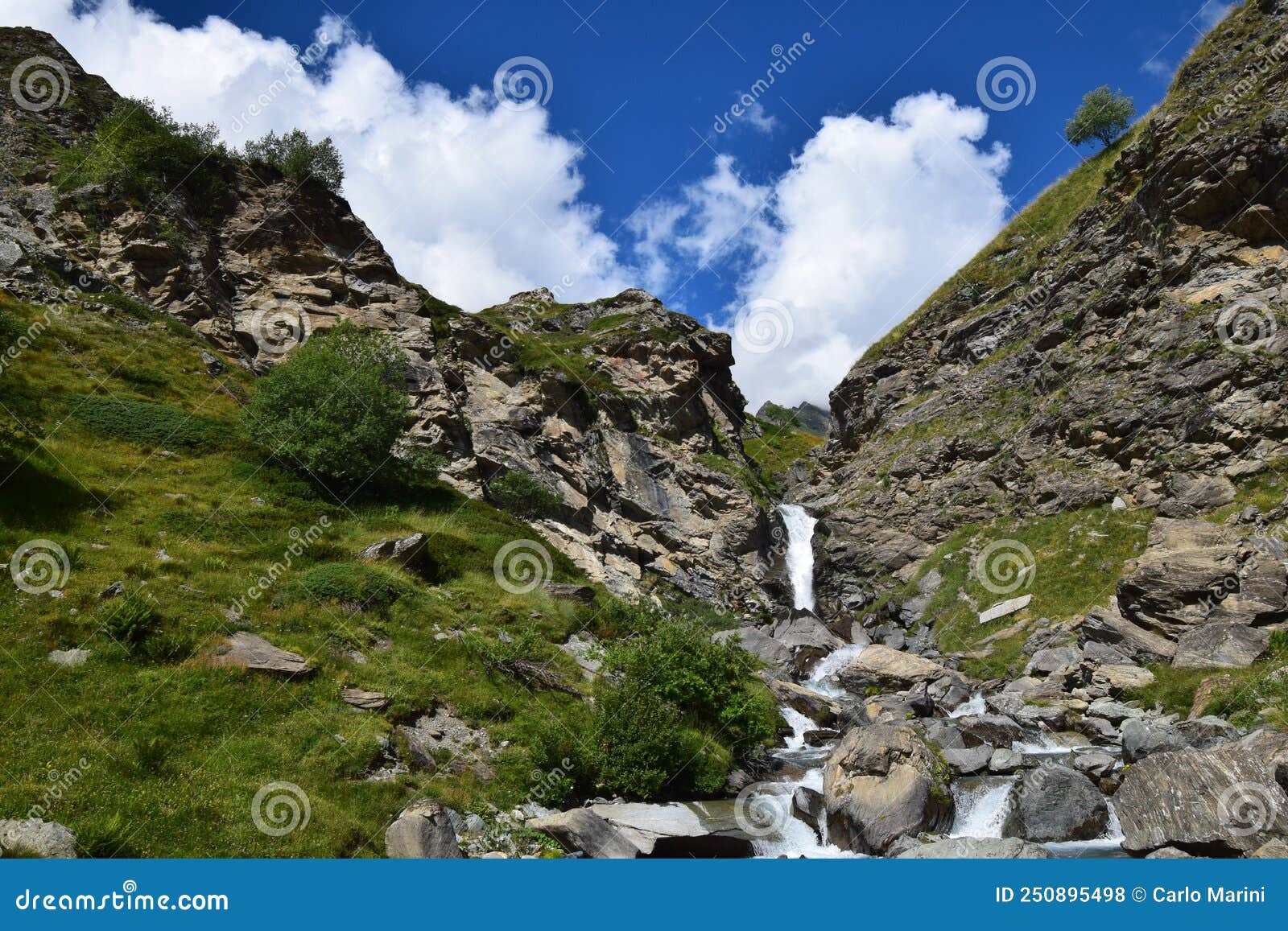 panorama delle alpi, cascata con cielo blu e nuvole bianche