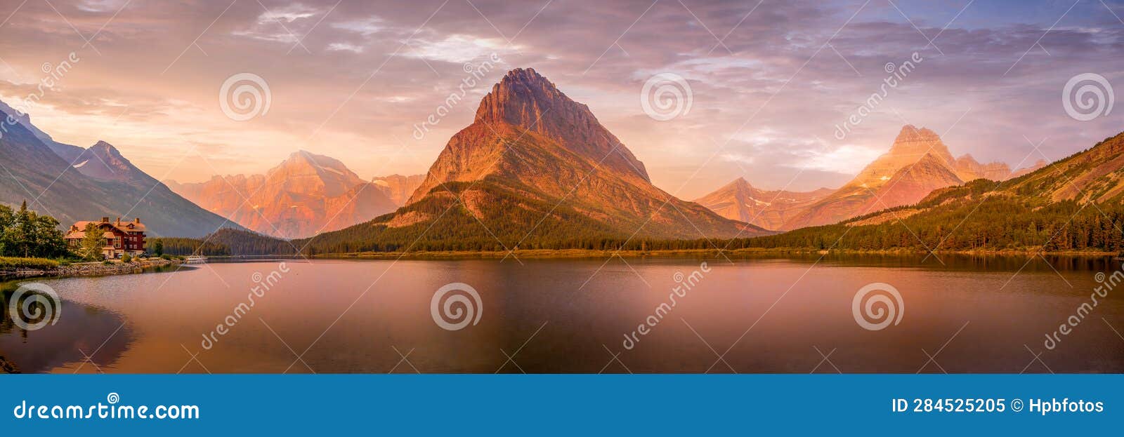 panorama landscape photo of sunrise over swiftcurrent lake and grinnell point