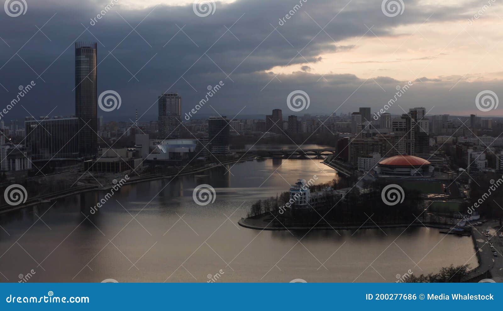 panorama of the pond and yekaterinburg iset skyscraper. stock footage. aerial view of dinamo building with round orange