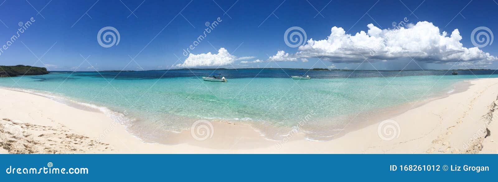 panorama of two boats anchored to turquoise waters off a white sand beach under a blue sky in abaco, bahamas