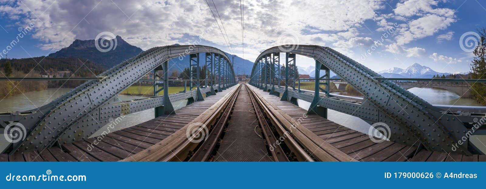panorama view to old metallic railway bridge with risty rails over rural river lech
