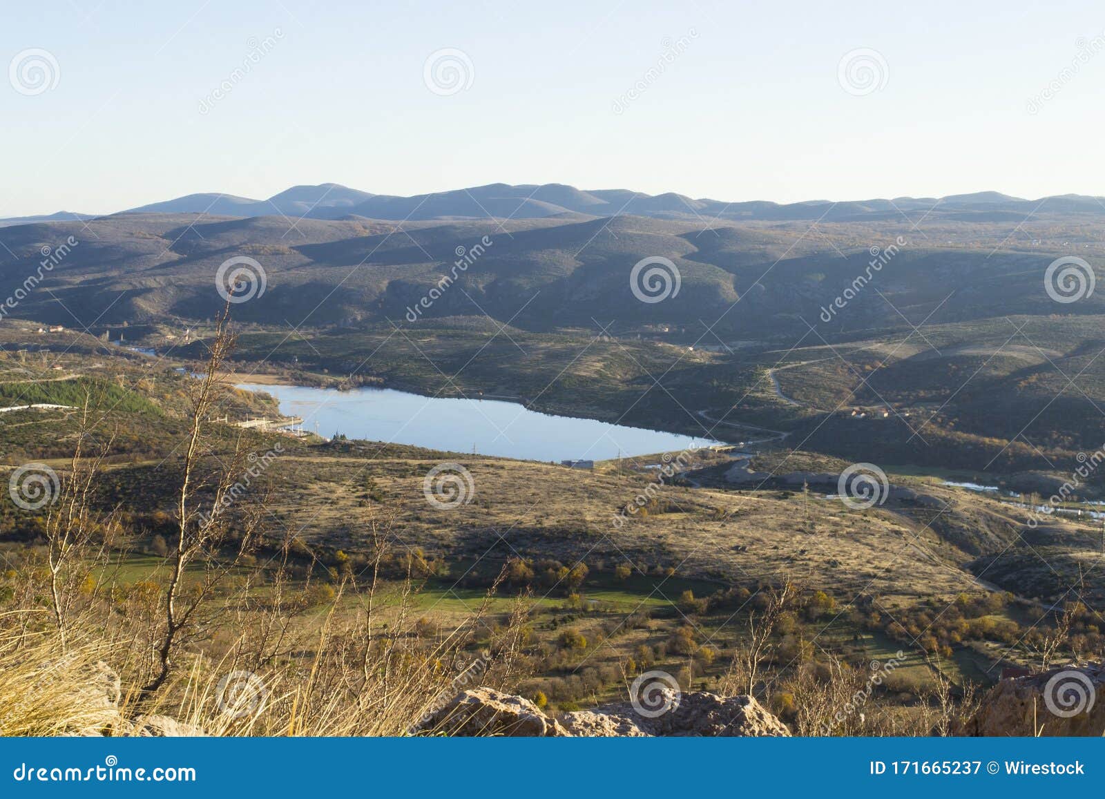 Panoramic Shot of a Lake between Rolling Hills Under a Cloudy Sky Stock