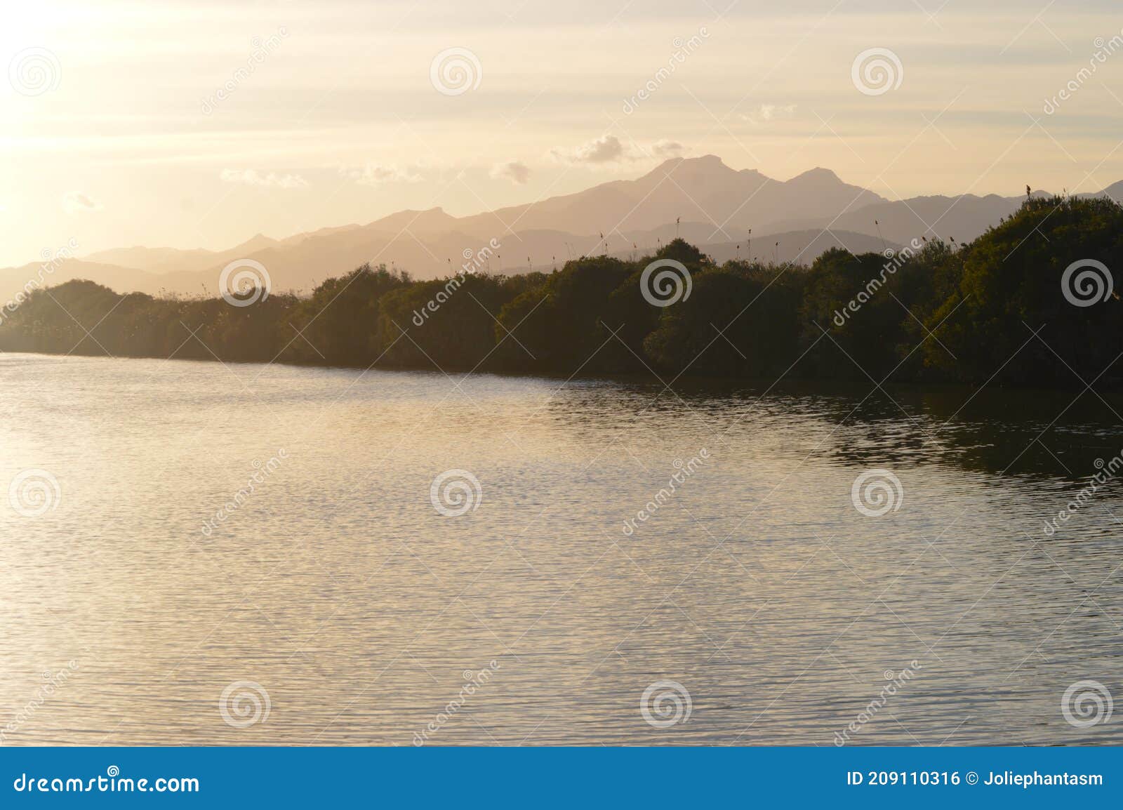 paradisiac sunset over the river and mountains with golden sky