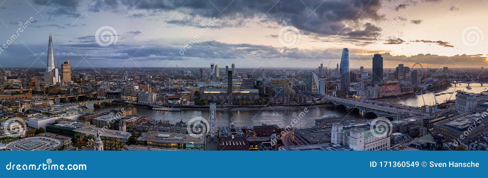 Panoramic view of the illuminated skyline of London, UK, from London Bridge to Westminster along the Thames river during evening