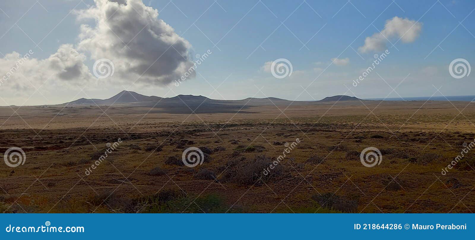 panoramica di paesaggio desertico con vulcani e nuvola