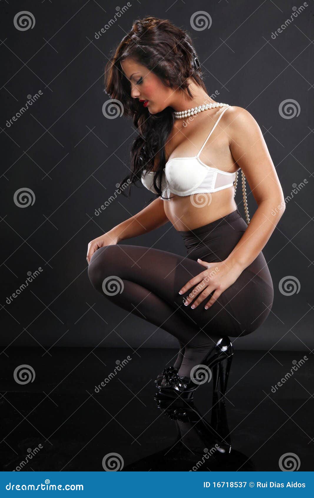 beautiful girl in a bra and pantyhose sits in a chair Stock Photo