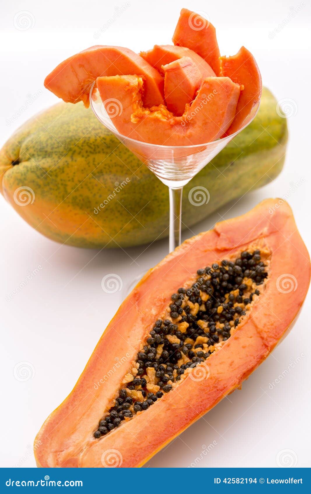 Papaya - a popular breakfast fruit. The oblong shape of half a papaya and its fruit flesh in a glass. The depth of field is running across both the papaya slices and the pulp revealed by the longitudinal section of the halved fruit.