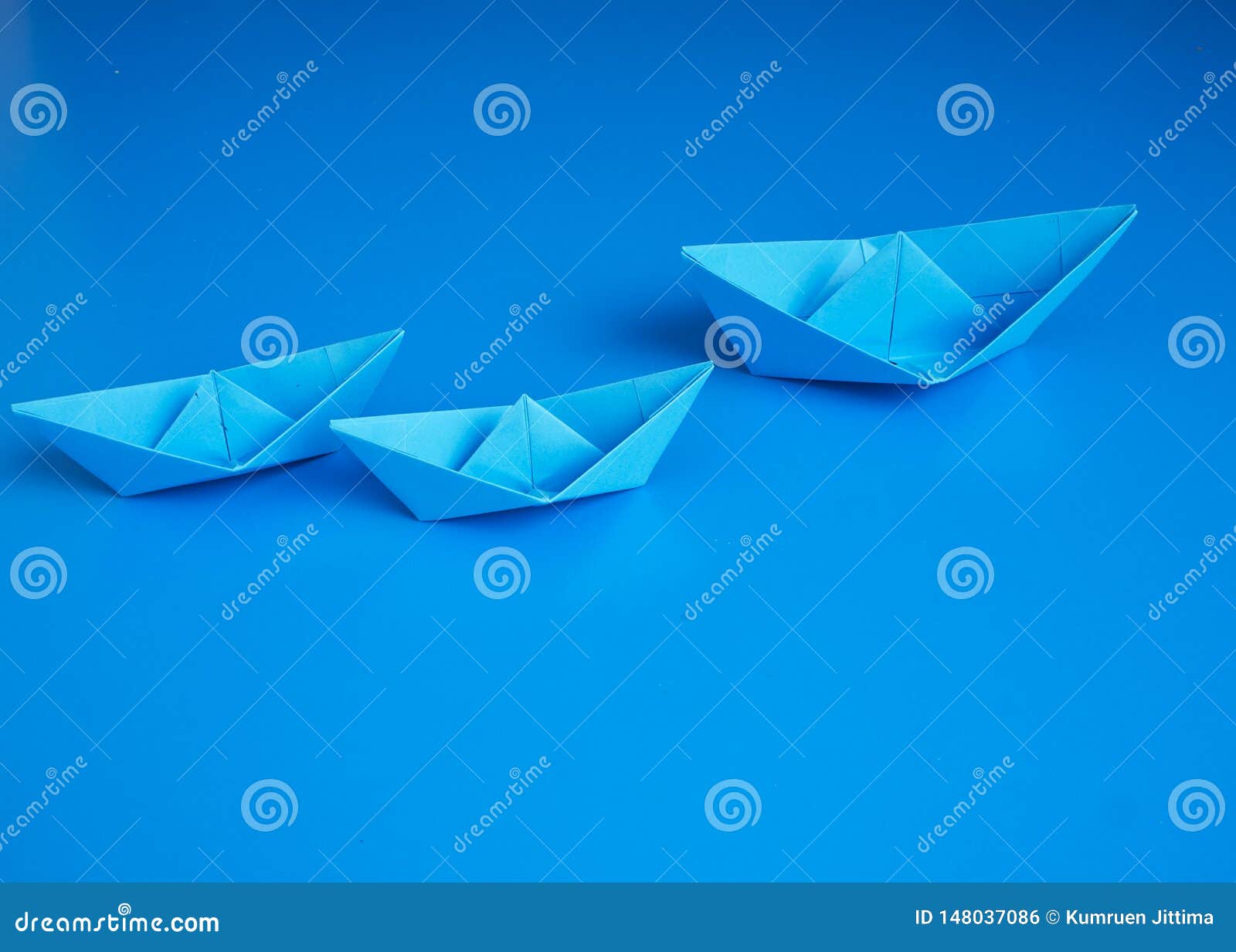 Monopoly business origami boat paper. Transnational monopoly business concept origami blue boats paper on blue background