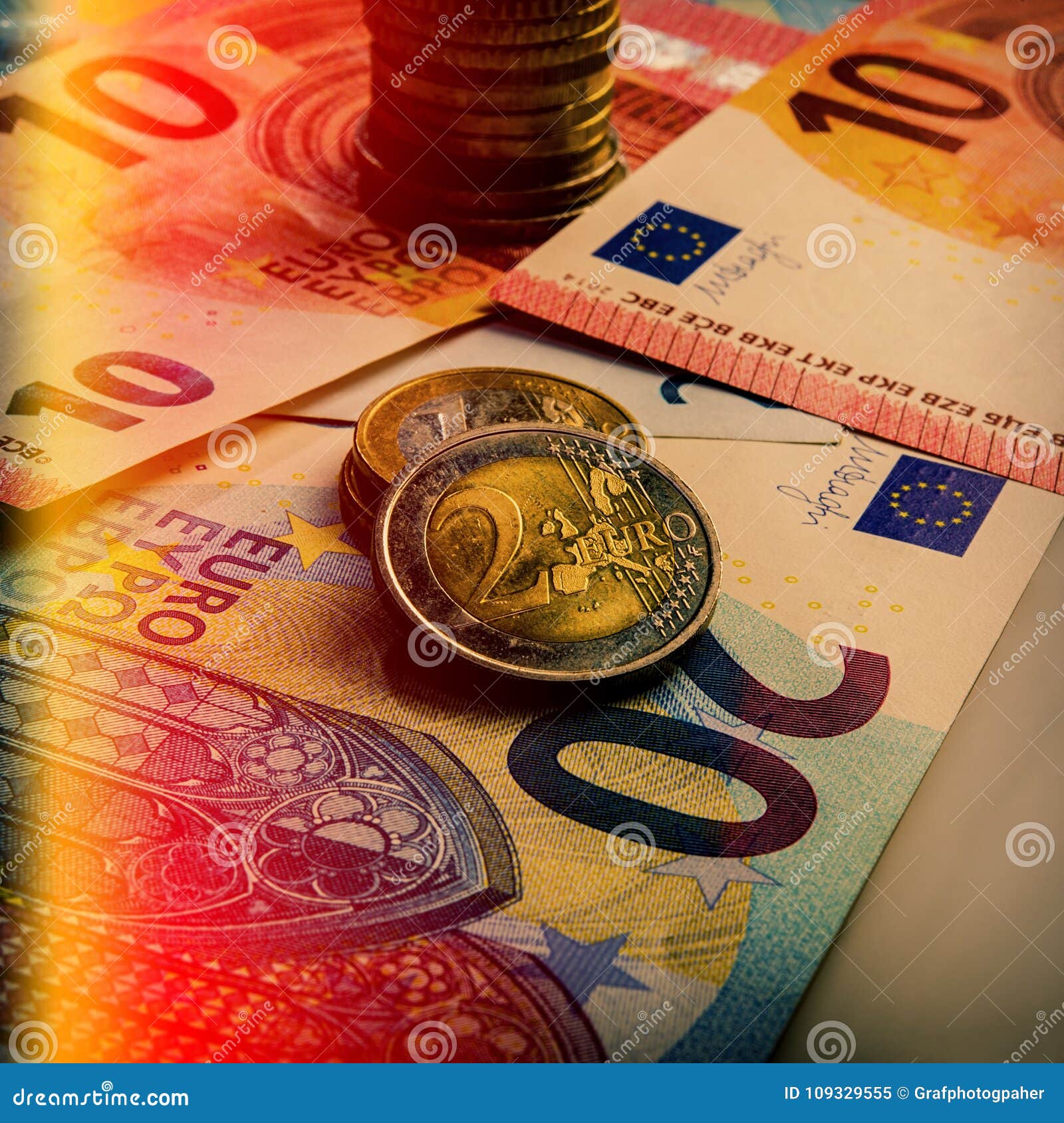 paper euro banknotes and coins. the coin is two euros.