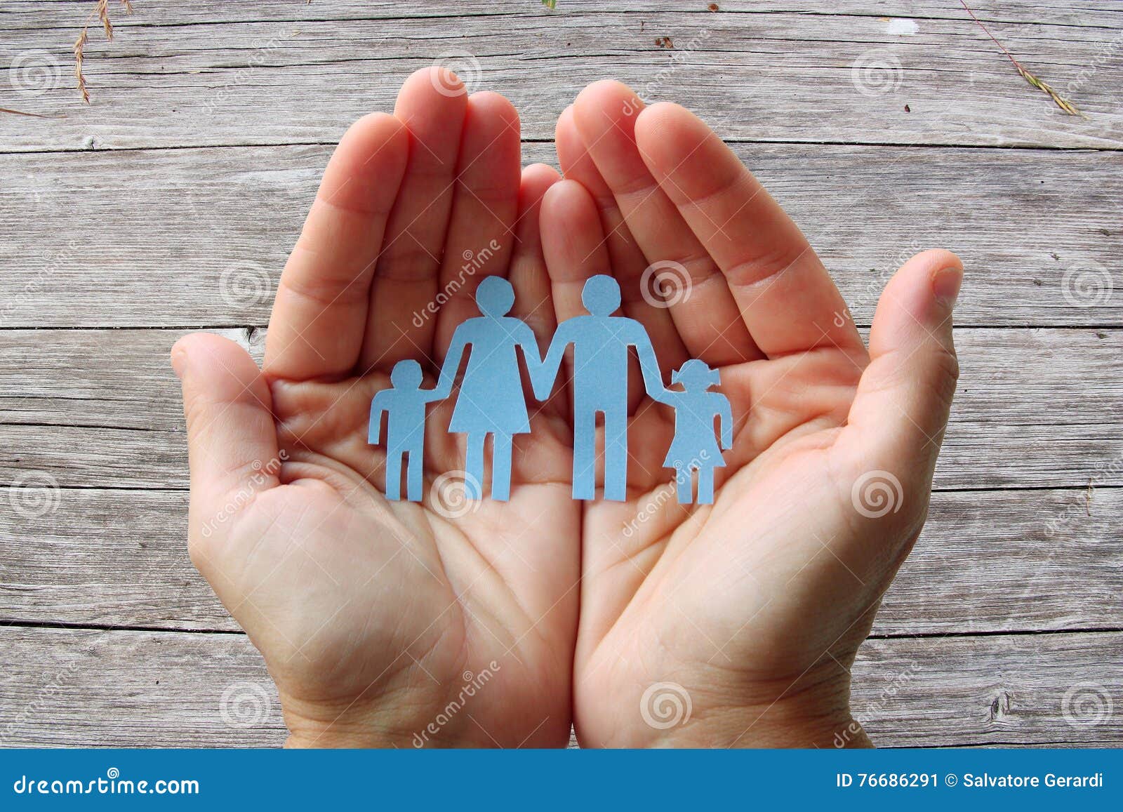 paper family in hands on wooden background welfare concept