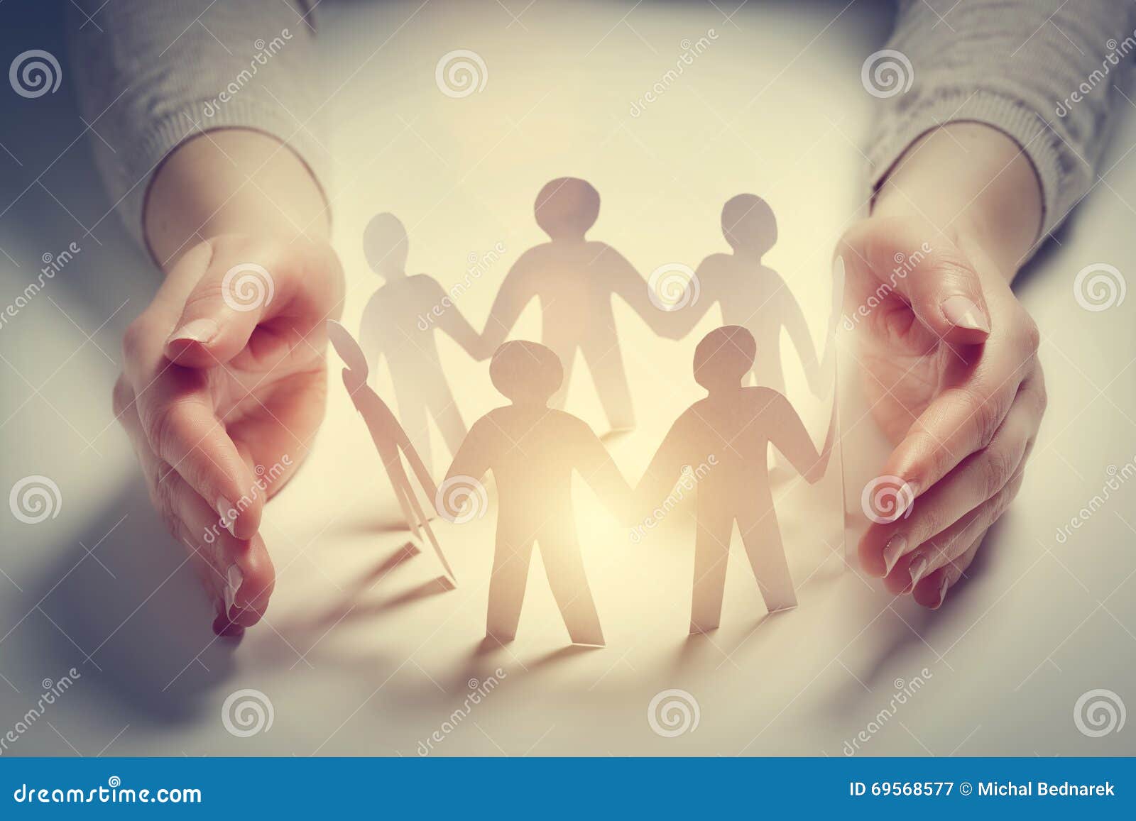paper people surrounded by hands in gesture of protection. concept of insurance