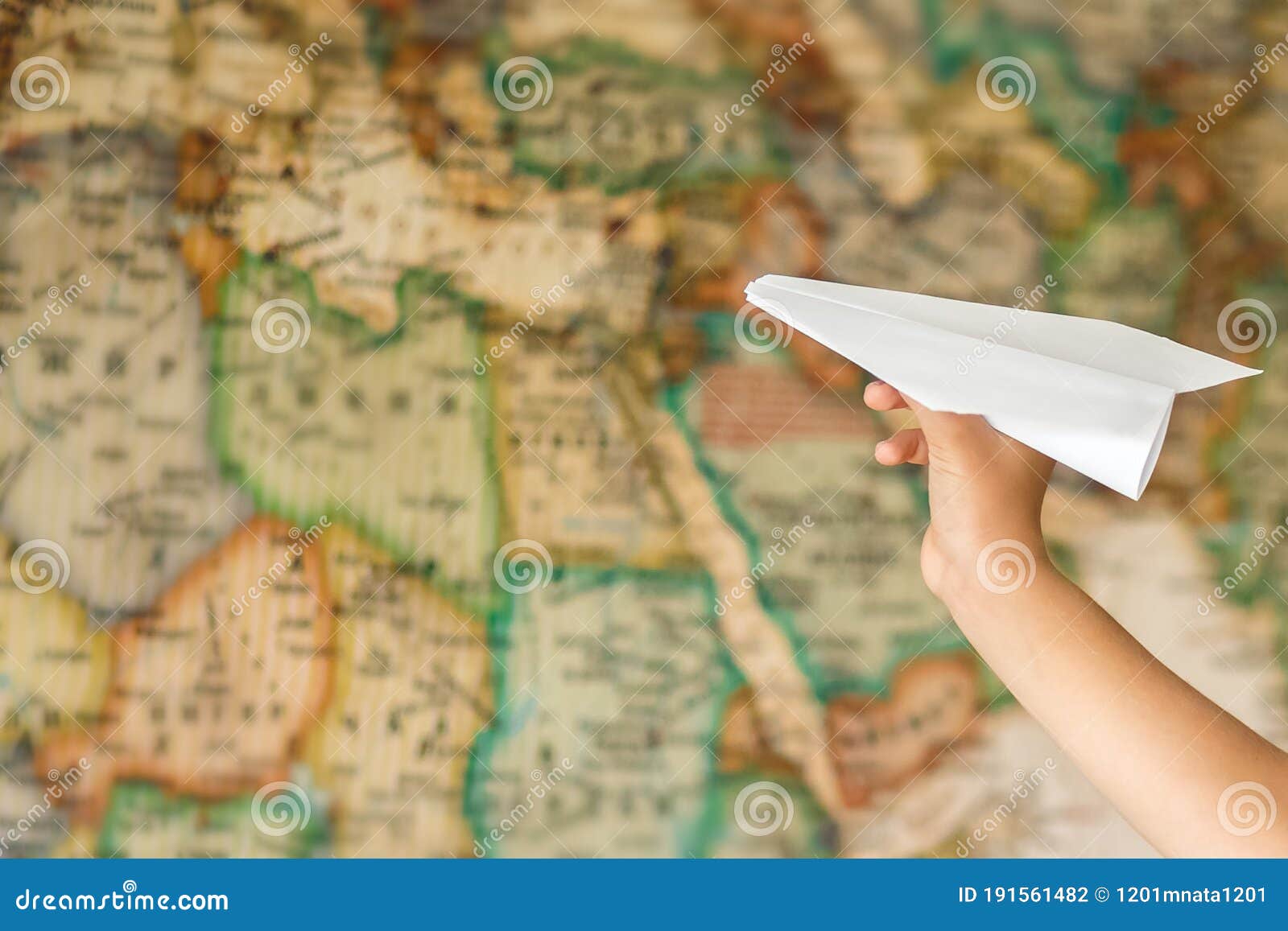 paper plane in hand on the background of the map. the map is blurred. purpose. dream to travel