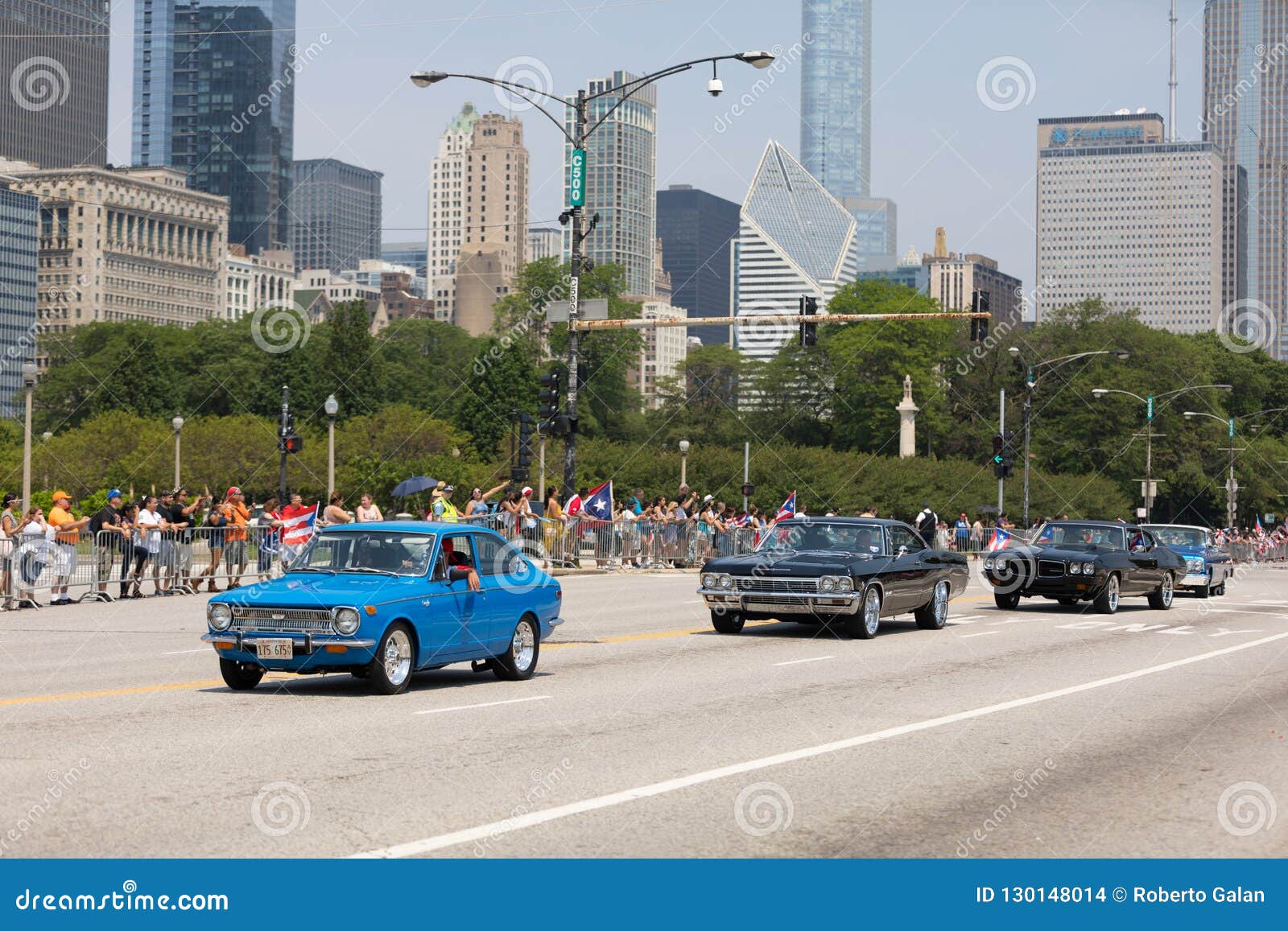 A parada porto-riquenha 2018 do dia. Chicago, Illinois, EUA - 16 de junho de 2018: A parada porto-riquenha do dia, porto-riquenho que conduz um carro clássico azul de Toyota Corolla com as bandeiras porto-riquenhas durante a parada