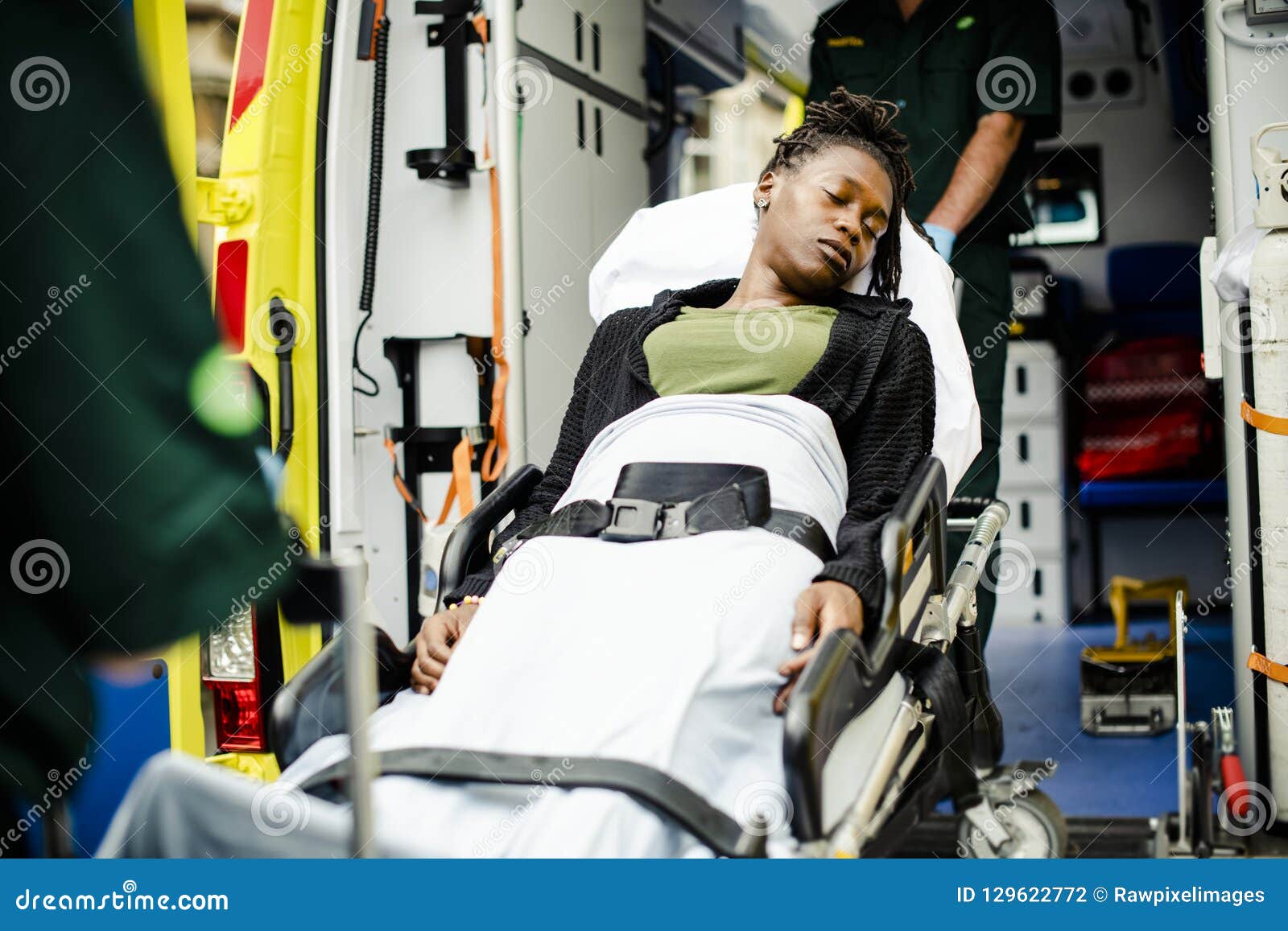 paramedics moving a patient on a stretcher into an ambulance