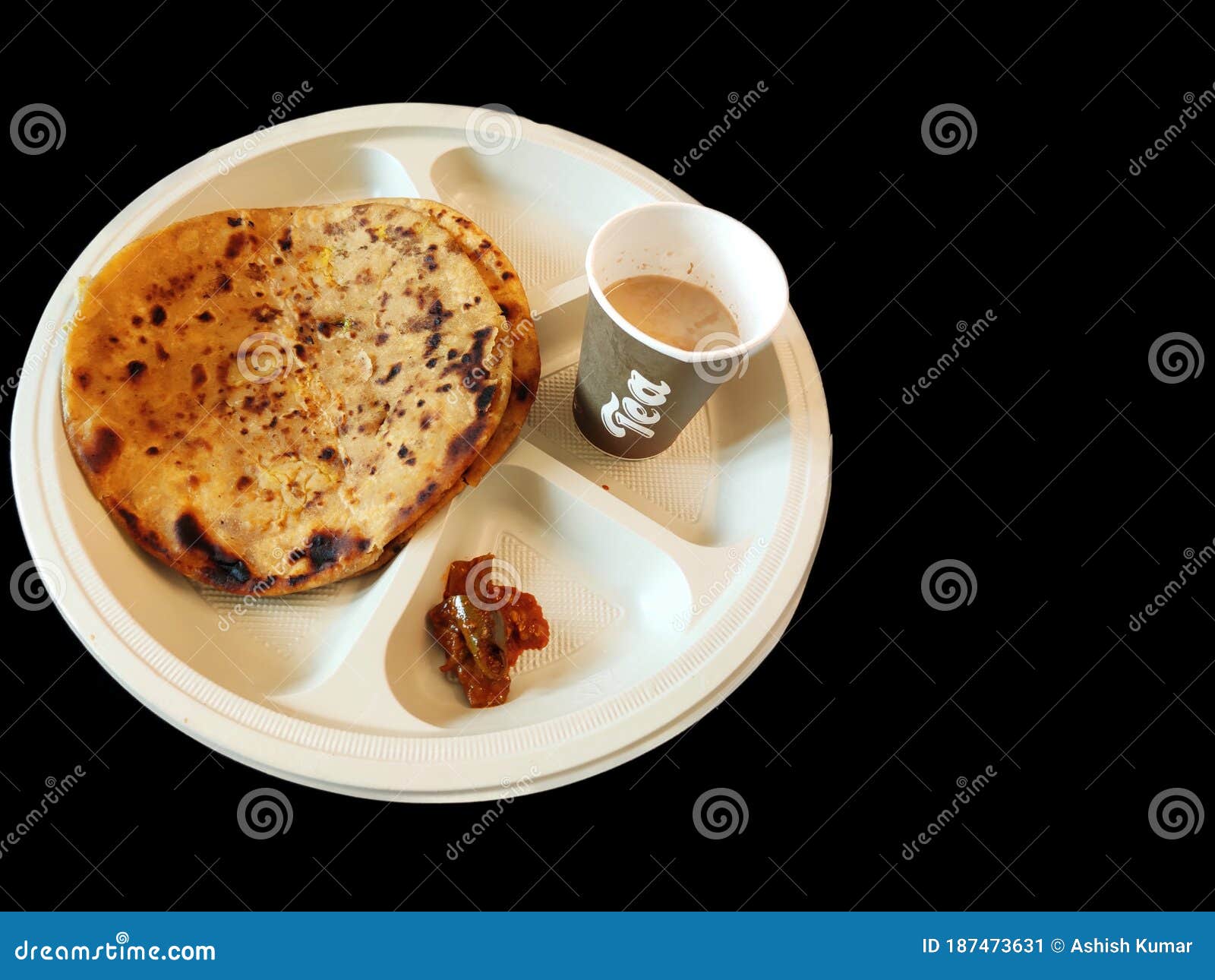 paratha chai with pickle in plate morning breakfast in india over dark black background with space for text
