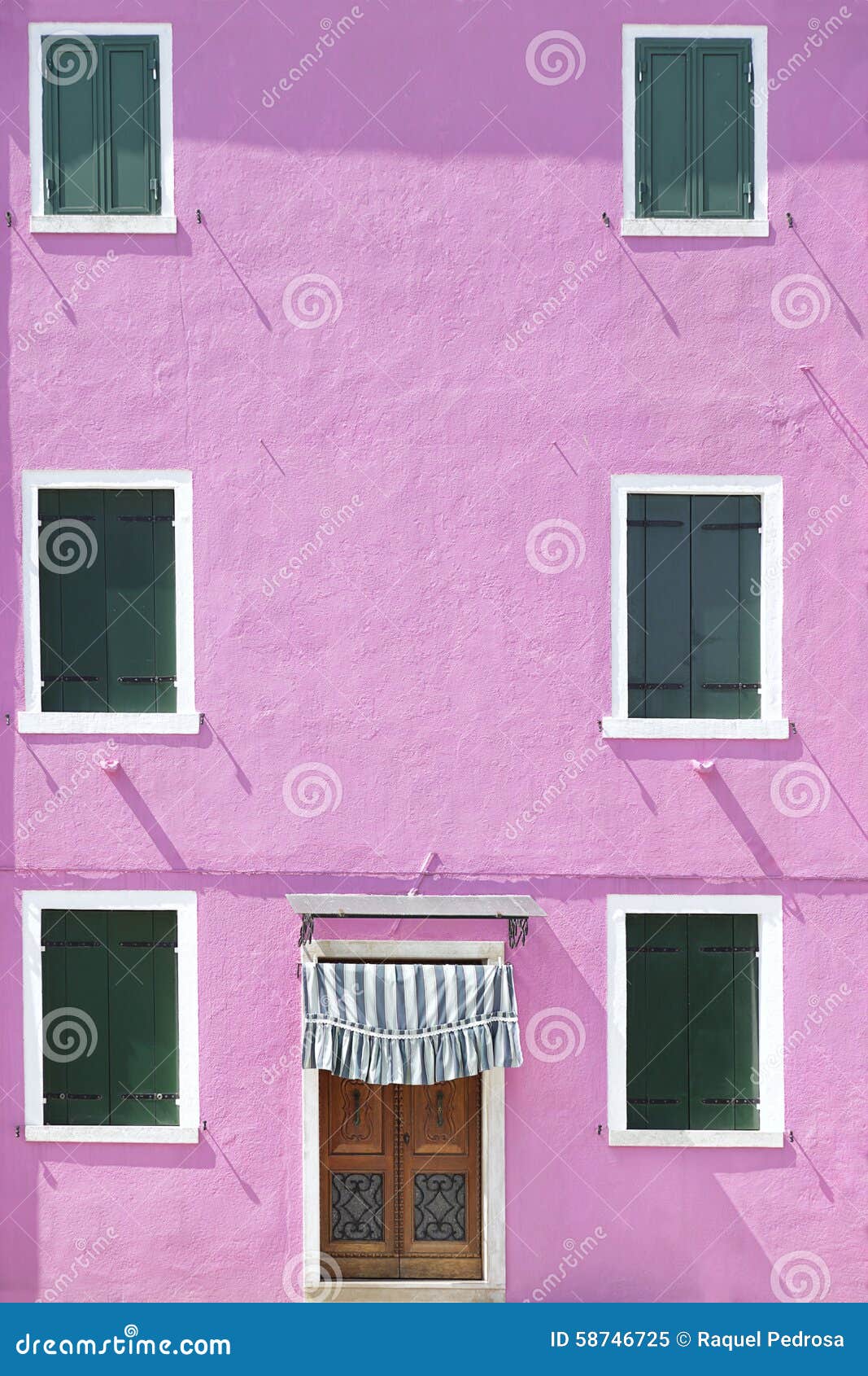 Pared pintada rosa con varias ventanas. Pique la pared pintada con varias ventanas con los obturadores de madera verdes, en la isla de Burano, Venecia, Italia