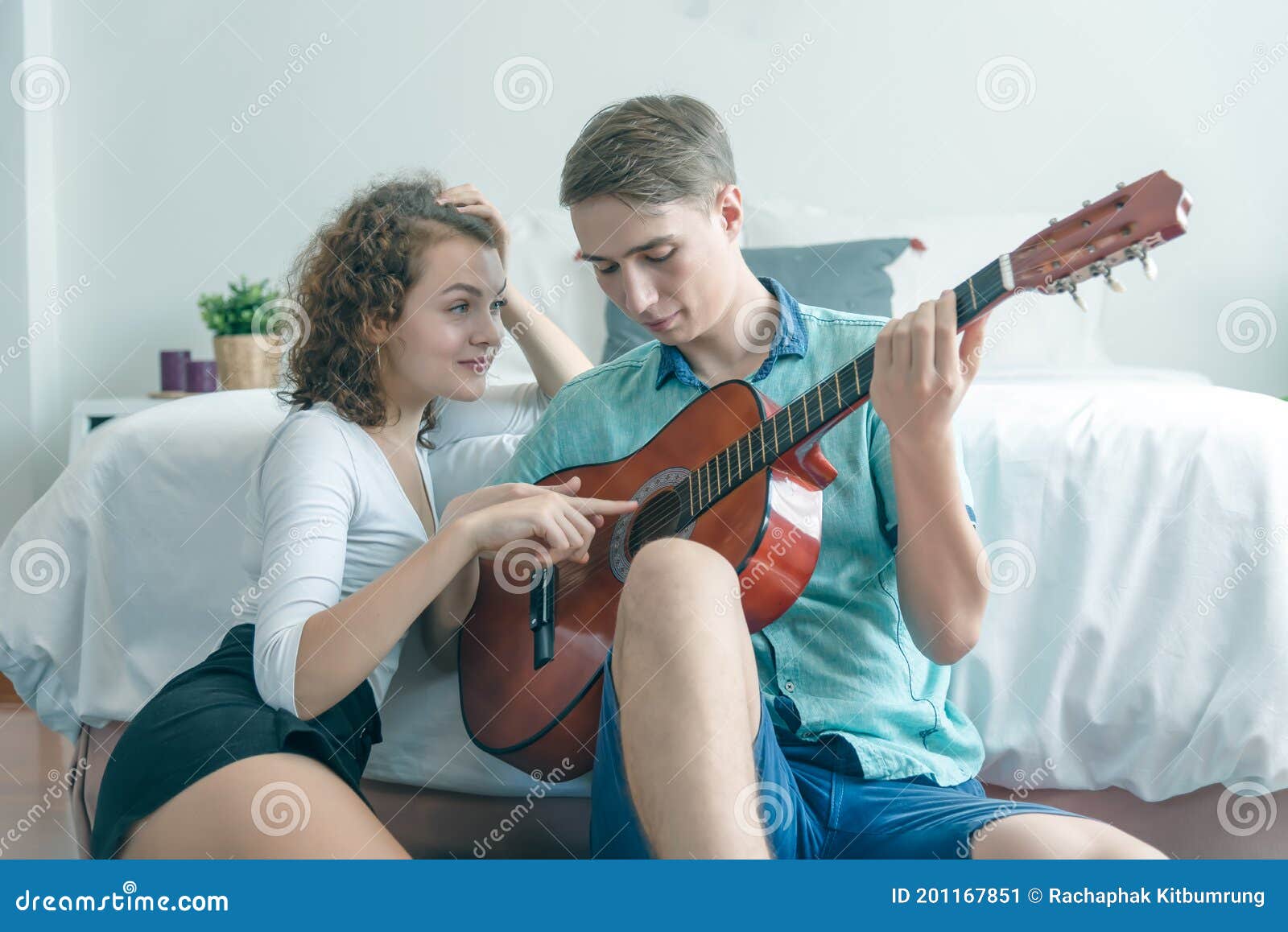 https://thumbs.dreamstime.com/z/pareja-joven-relajante-sentada-en-la-habitaci%C3%B3n-de-cama-tocando-guitarra-ac%C3%BAstica-hermosa-mujer-viendo-su-novio-y-un-hombre-201167851.jpg