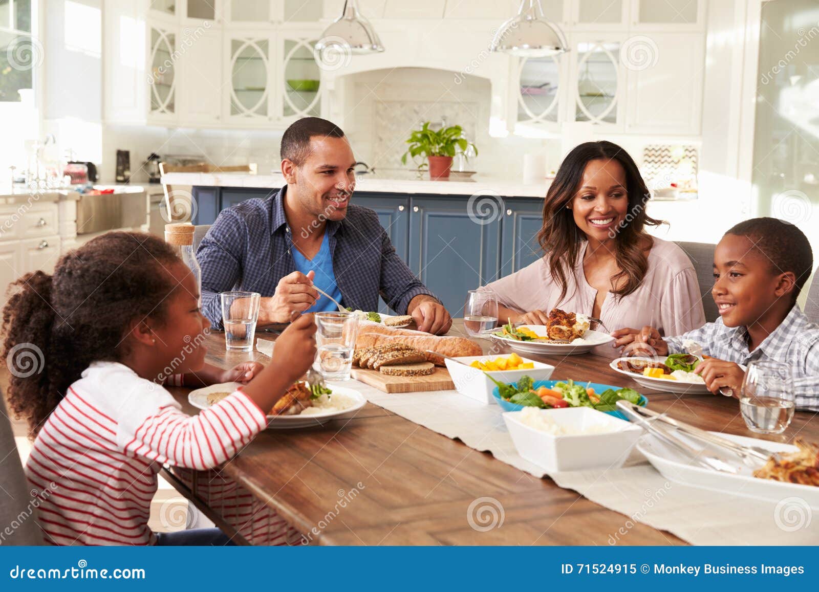 Parents and Their Two Children Eating at Kitchen Table Stock Image