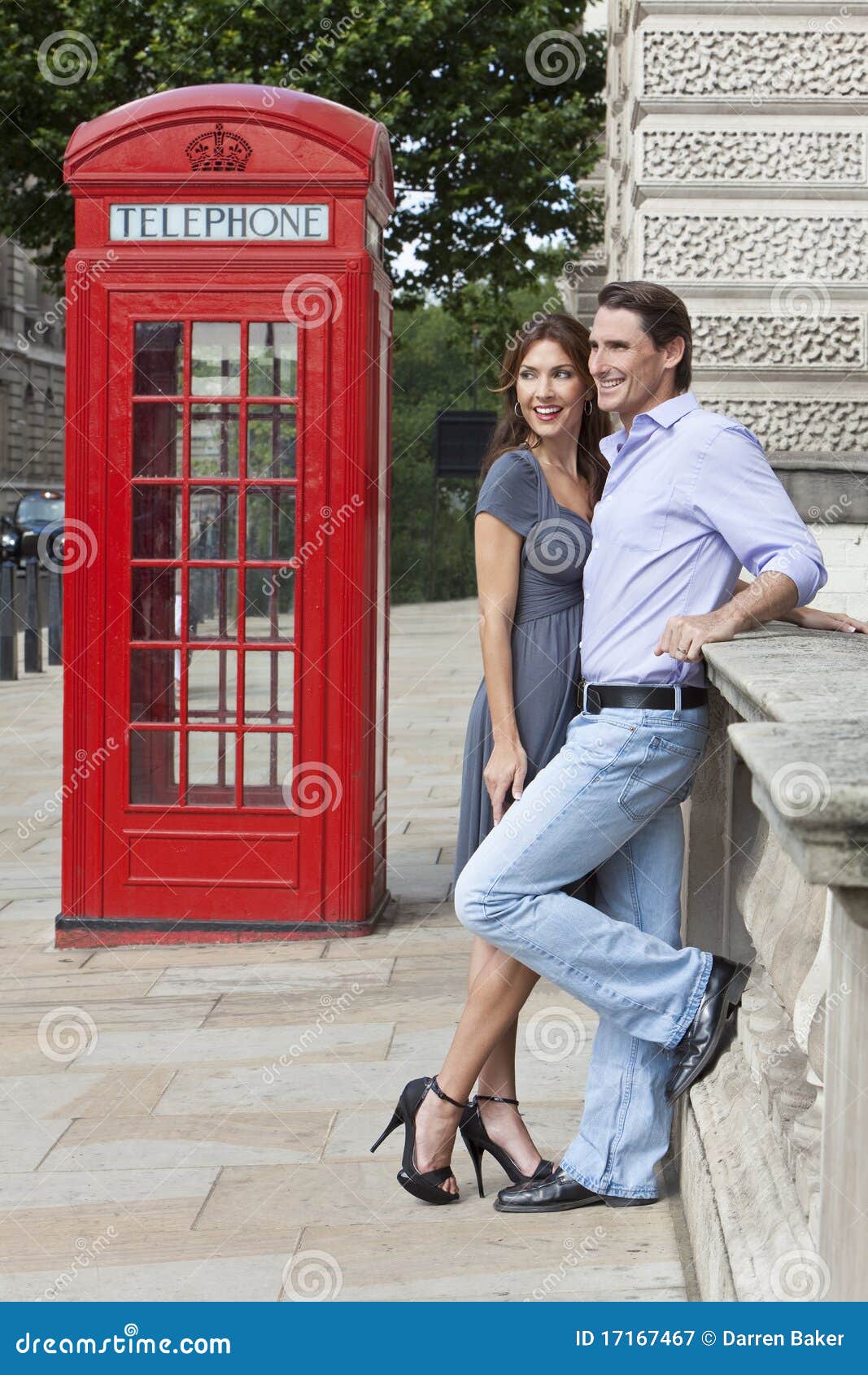 Pares &amp; caixa vermelha do telefone em Londres, Inglaterra. Pares românticos do homem e da mulher ao lado da caixa de telefone vermelha tradicional em Westminster, Londres, Inglaterra, Grâ Bretanha