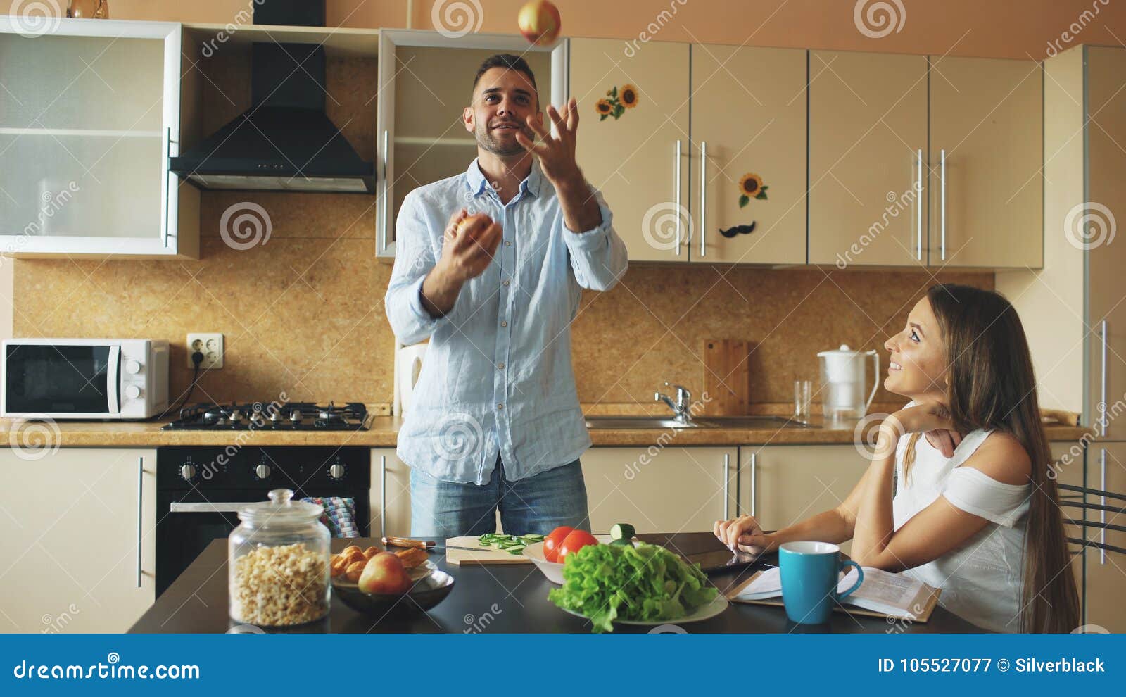 Pares Carinosos Atractivos Que Se Divierten En La Cocina El Hombre Hermoso Hace Juegos Malabares Con Las Manzanas Para Impresiona Imagen De Archivo Imagen De Carinosos Juegos 105527077