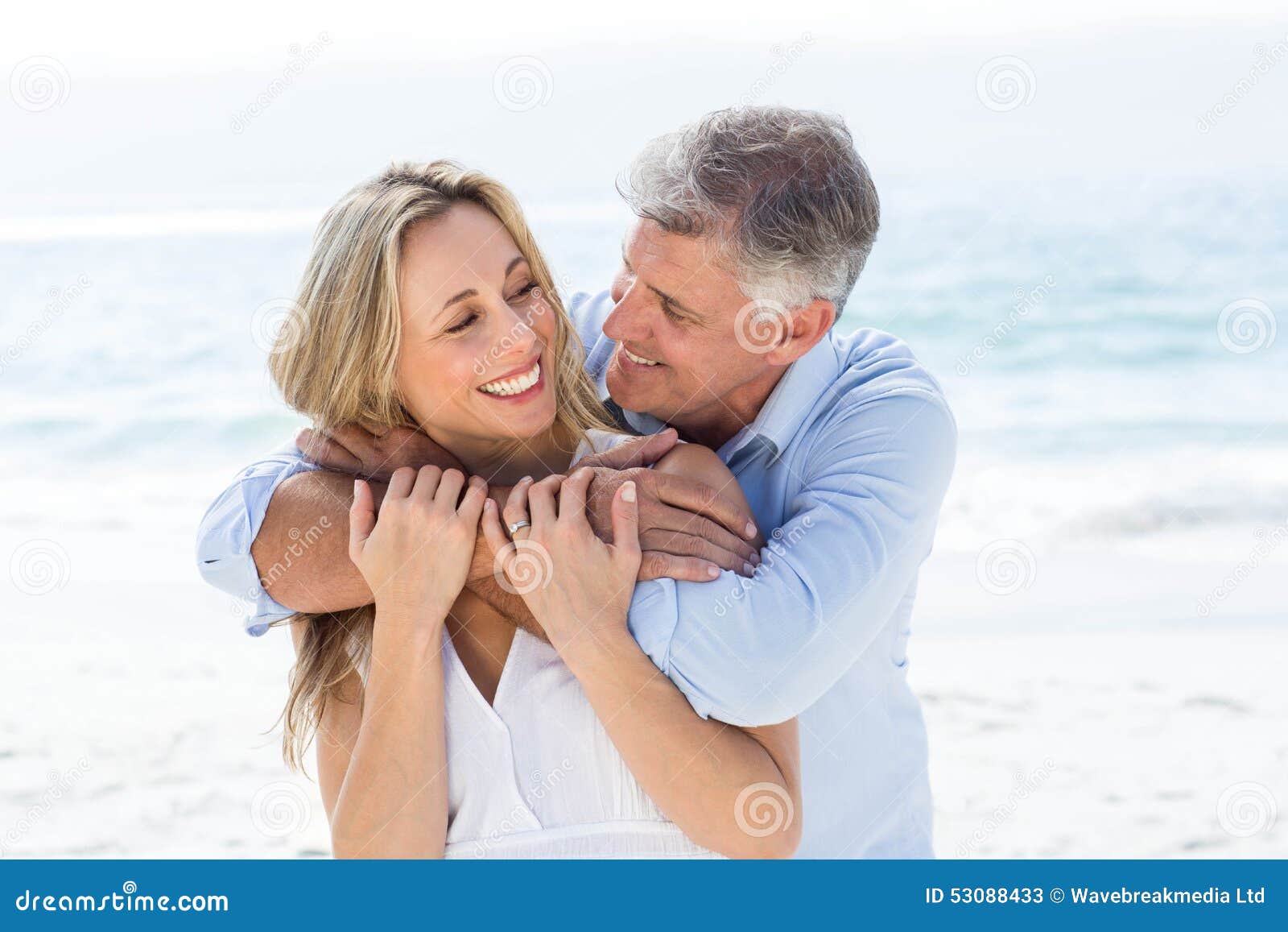 Pares felices que se abrazan por el mar en la playa