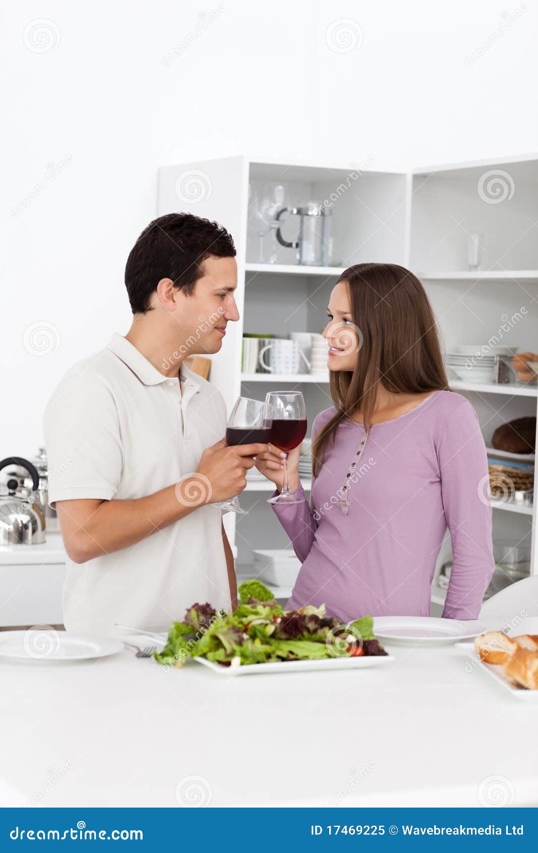 Pares jovenes que dan una tostada durante el almuerzo en la cocina