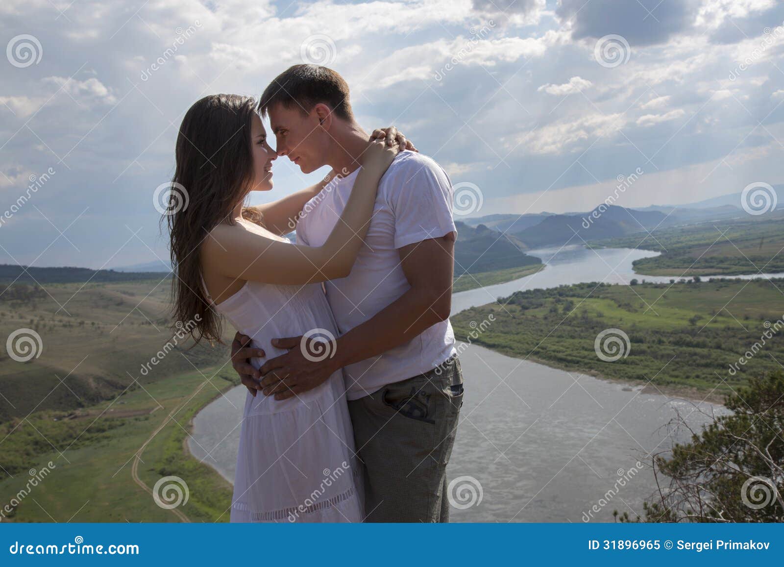 Pares novos que abraçam nas montanhas. Pares novos felizes que abraçam nas montanhas com o rio no fundo