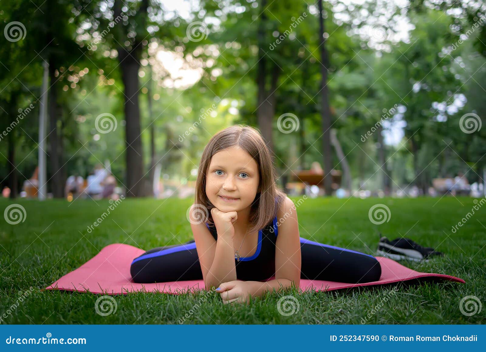 In the Park, a Little Girl Performs a Frog Element, Doing Stretching on ...