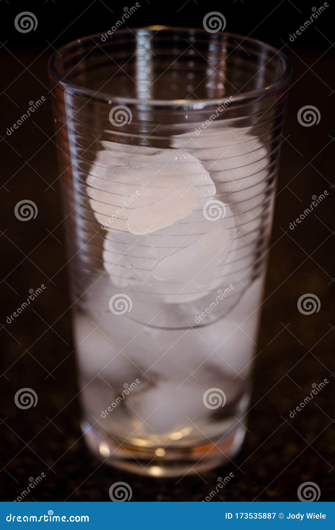 partially melted ice cubes in a glass with a dark background
