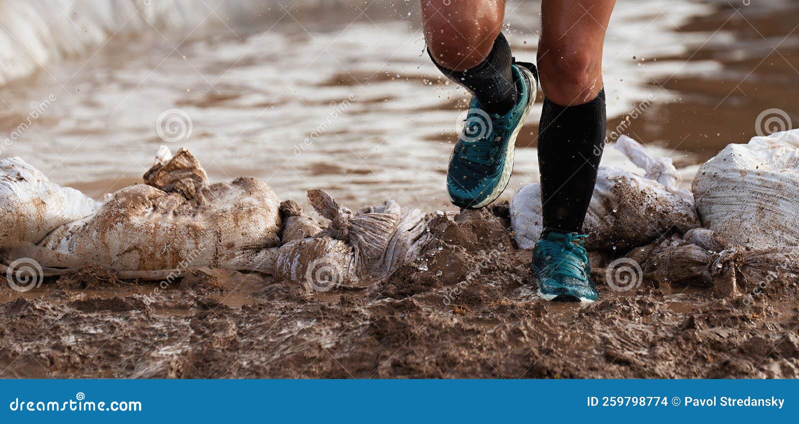 participant in an obstacle course race runs out of a water obstacle