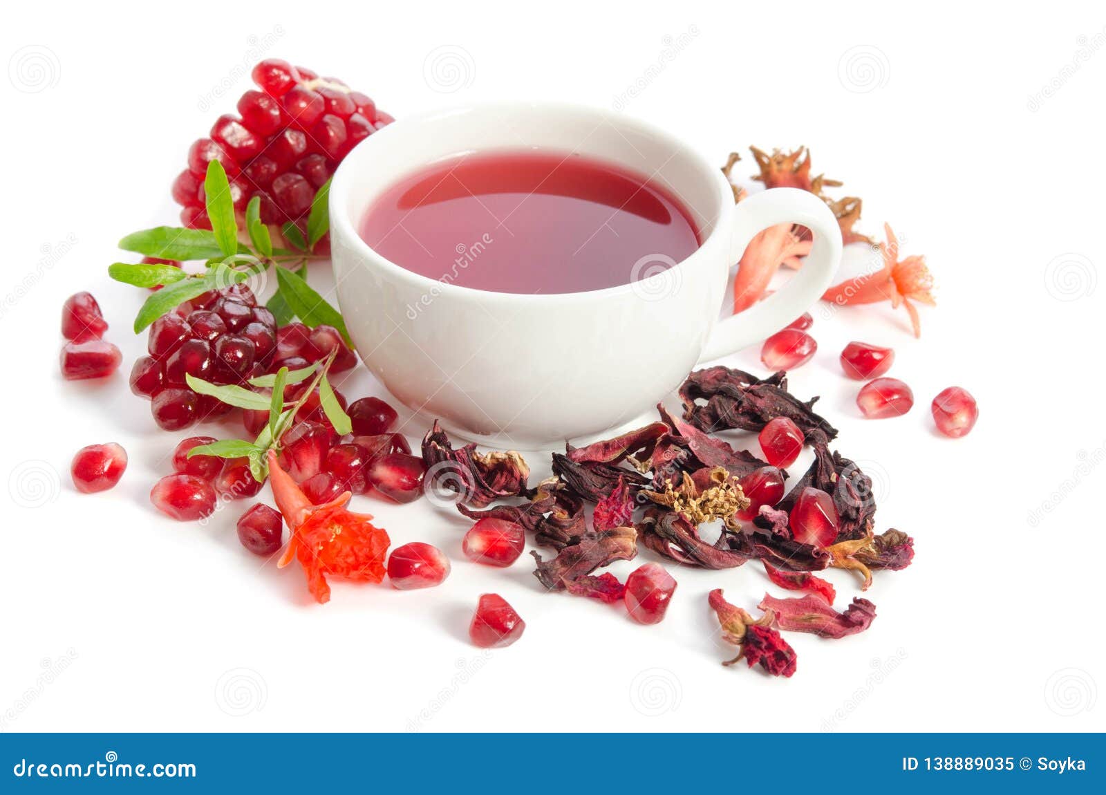 parts of pomegranate with pomegranate seeds and leaves, flowers, dry tea of carcade and full cup of tea on white