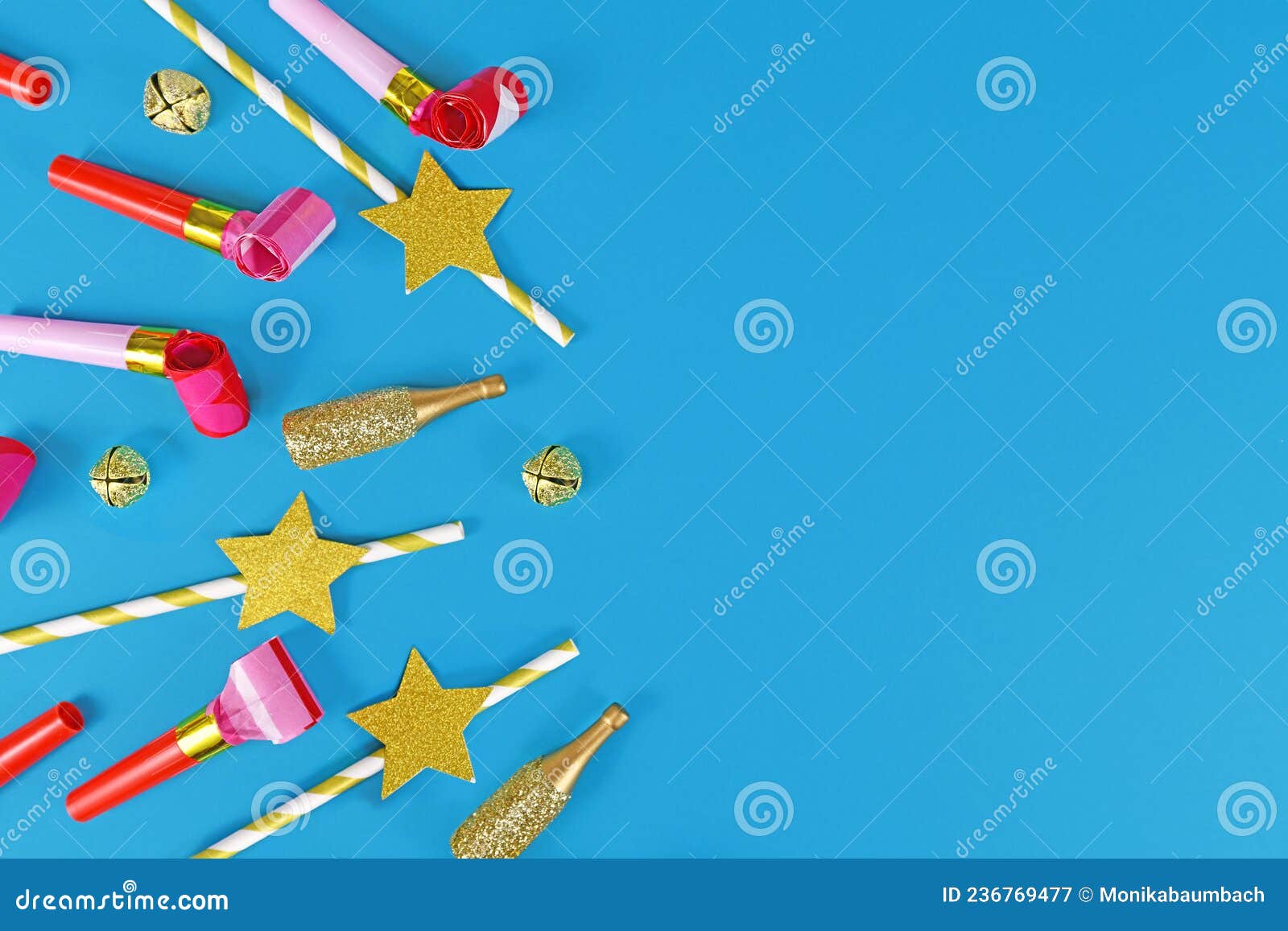 party flat lay with blowouts, champagne bottles, drinking straws and bells on side of blue background