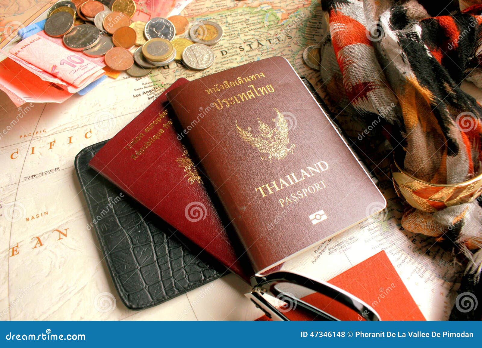 pasport with the s of thailand and republique francaise and some coins on world map.