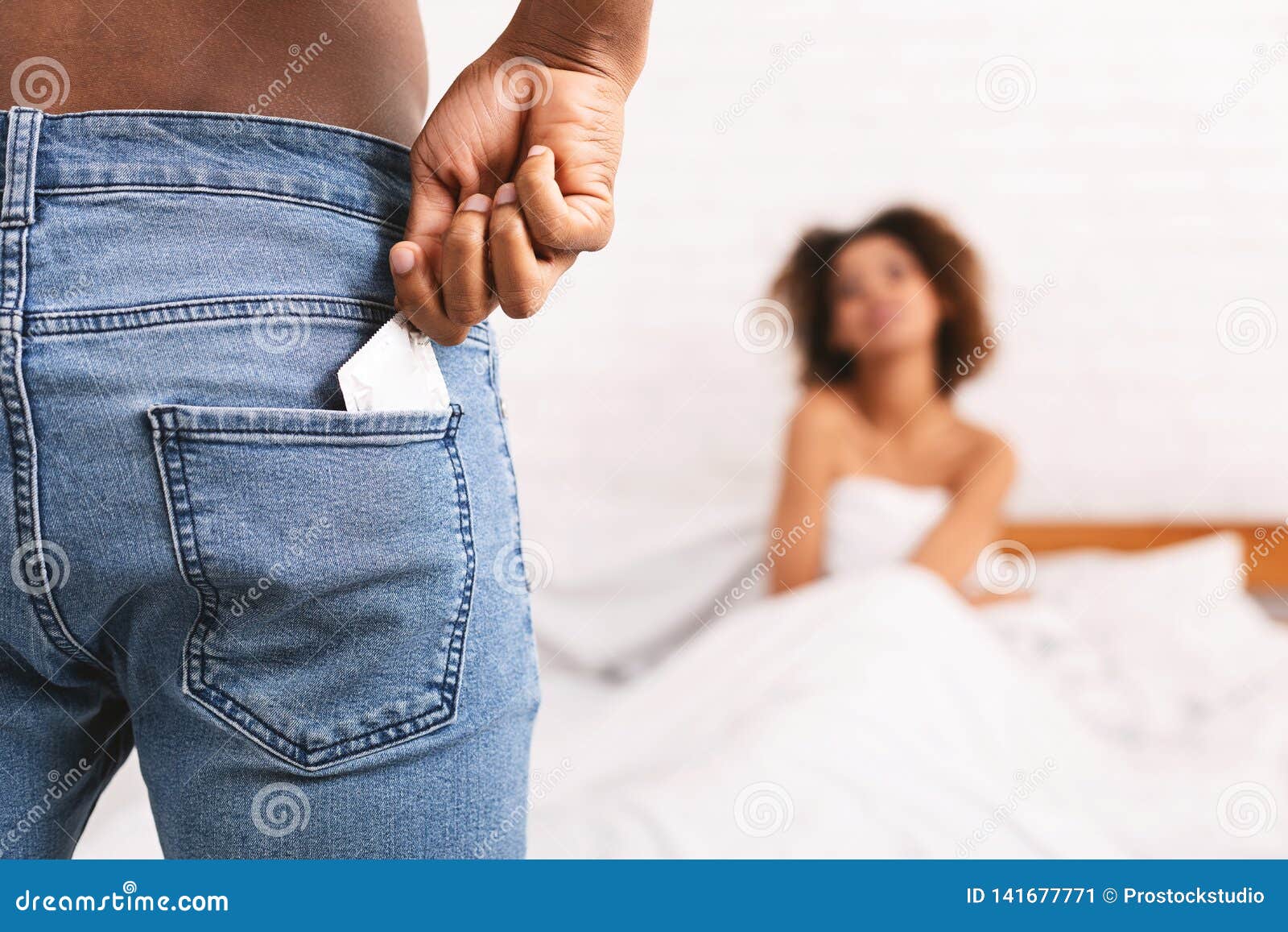 Man Taking Condom from Jeans, Woman Waiting in Bed Stock Image