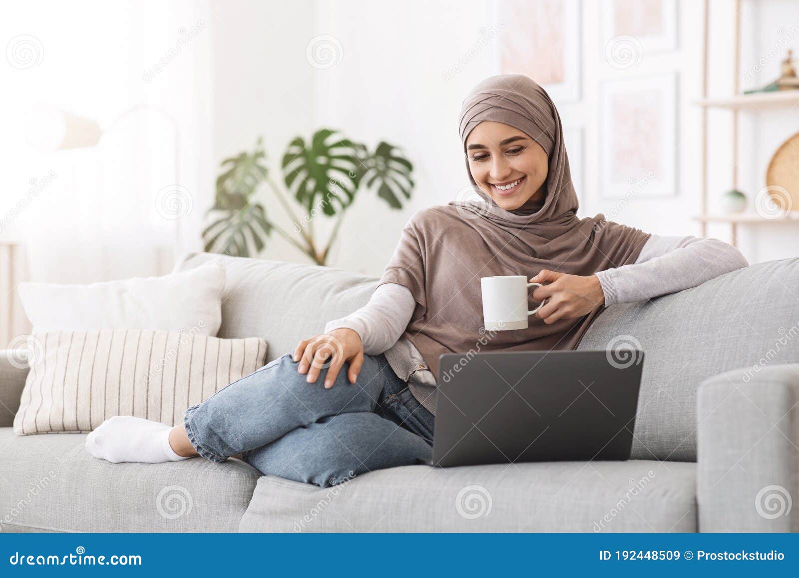 home passtime . cheerful arabic woman watching movies on laptop and drinking coffee