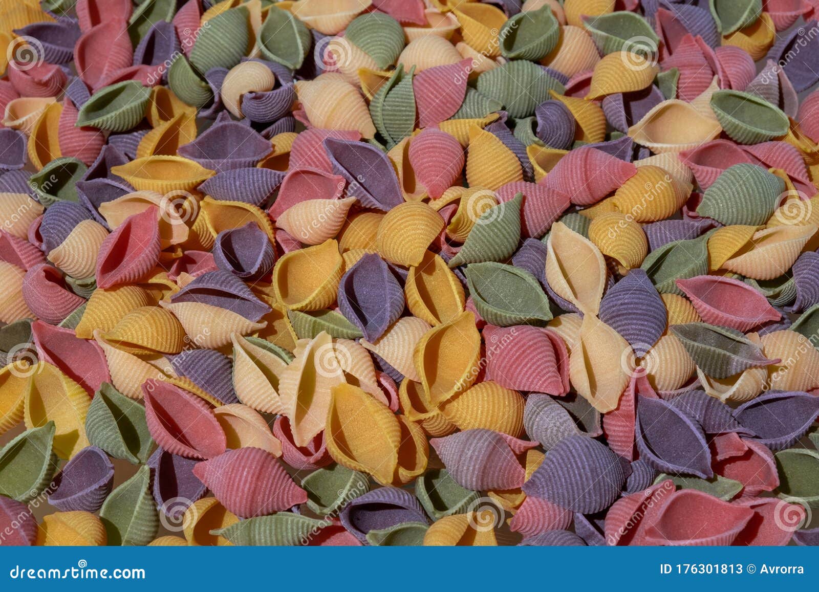 pasta conchiglie rigate, mix of colorful uncooked shells with spinach and tomatoes. textured italian food background concept