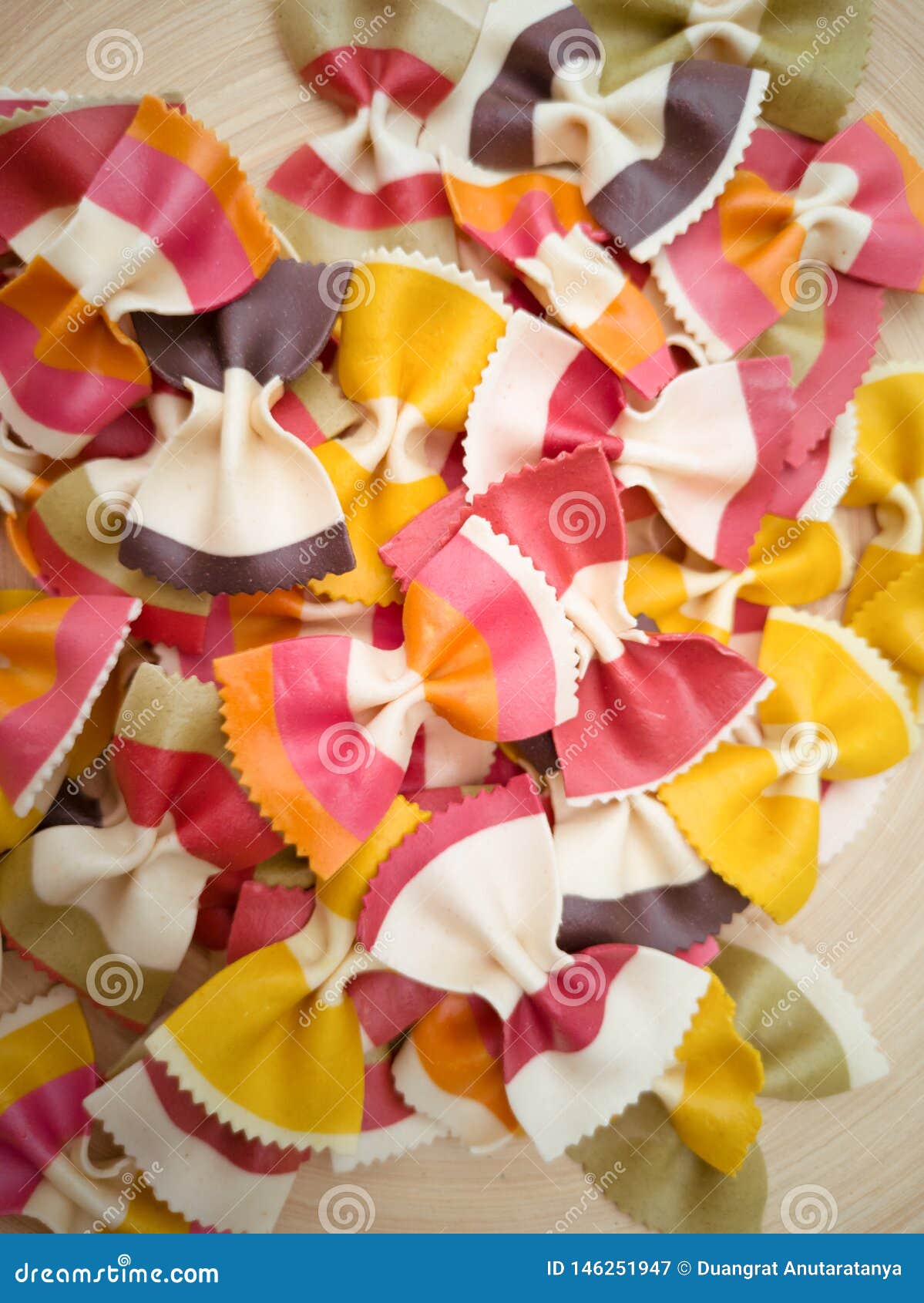 pasta farfalle,italian pasta pattern on a wood plate. various colors of bow tie farfalle pasta viewed from above. top view. repeti