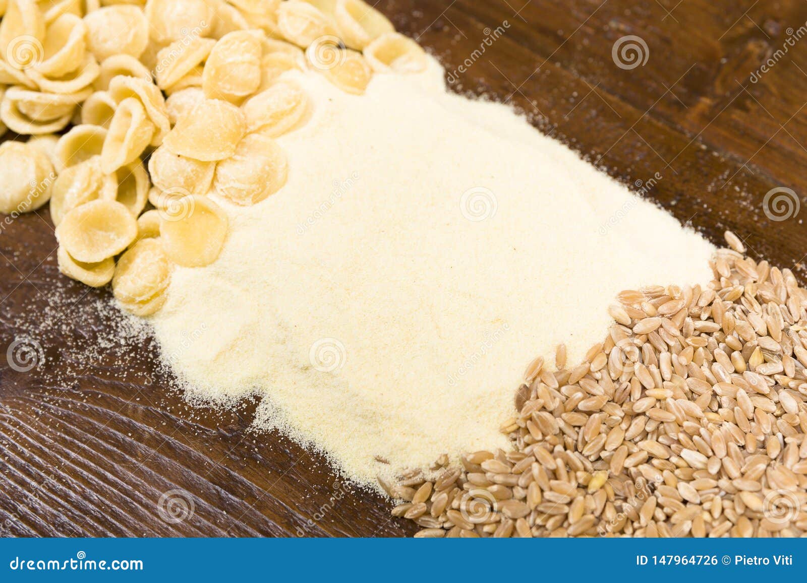 wheat grains, pasta and flour on a wooden table