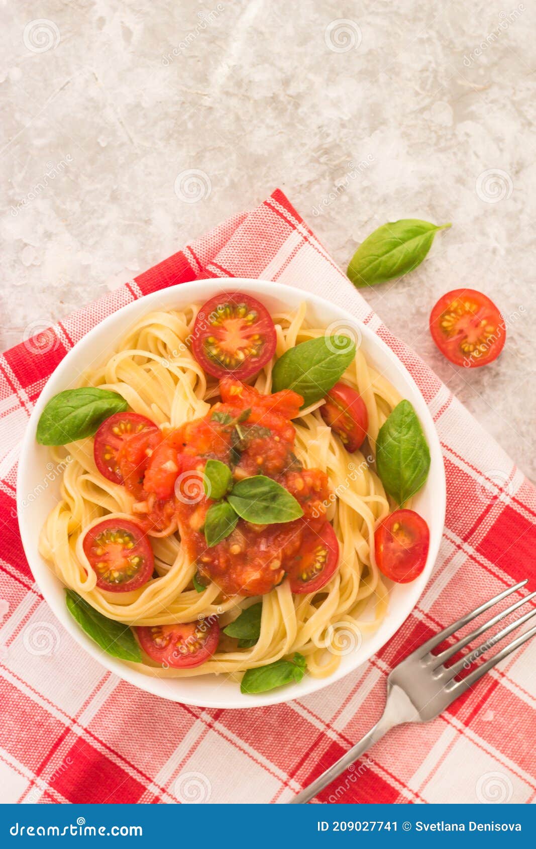 Pasta Marinara in a White Plate on a White Table with Tomato Wedges and