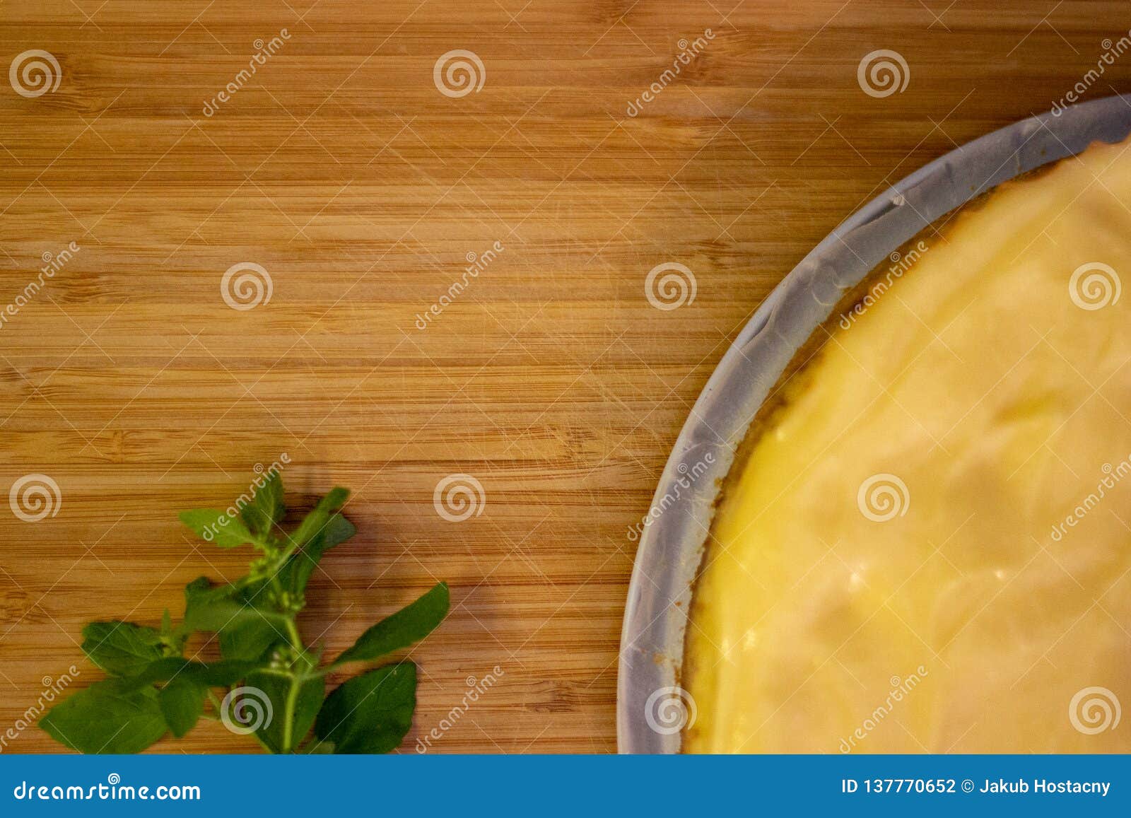 Pastel de queso en la madera. Pastel de queso del limón en el escritorio del bambus con el pedazo verde de pepermint