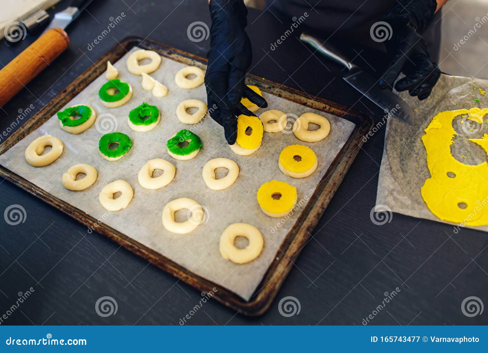 Pastelaria decora profiteroles crus com massa de caroço verde e amarelo