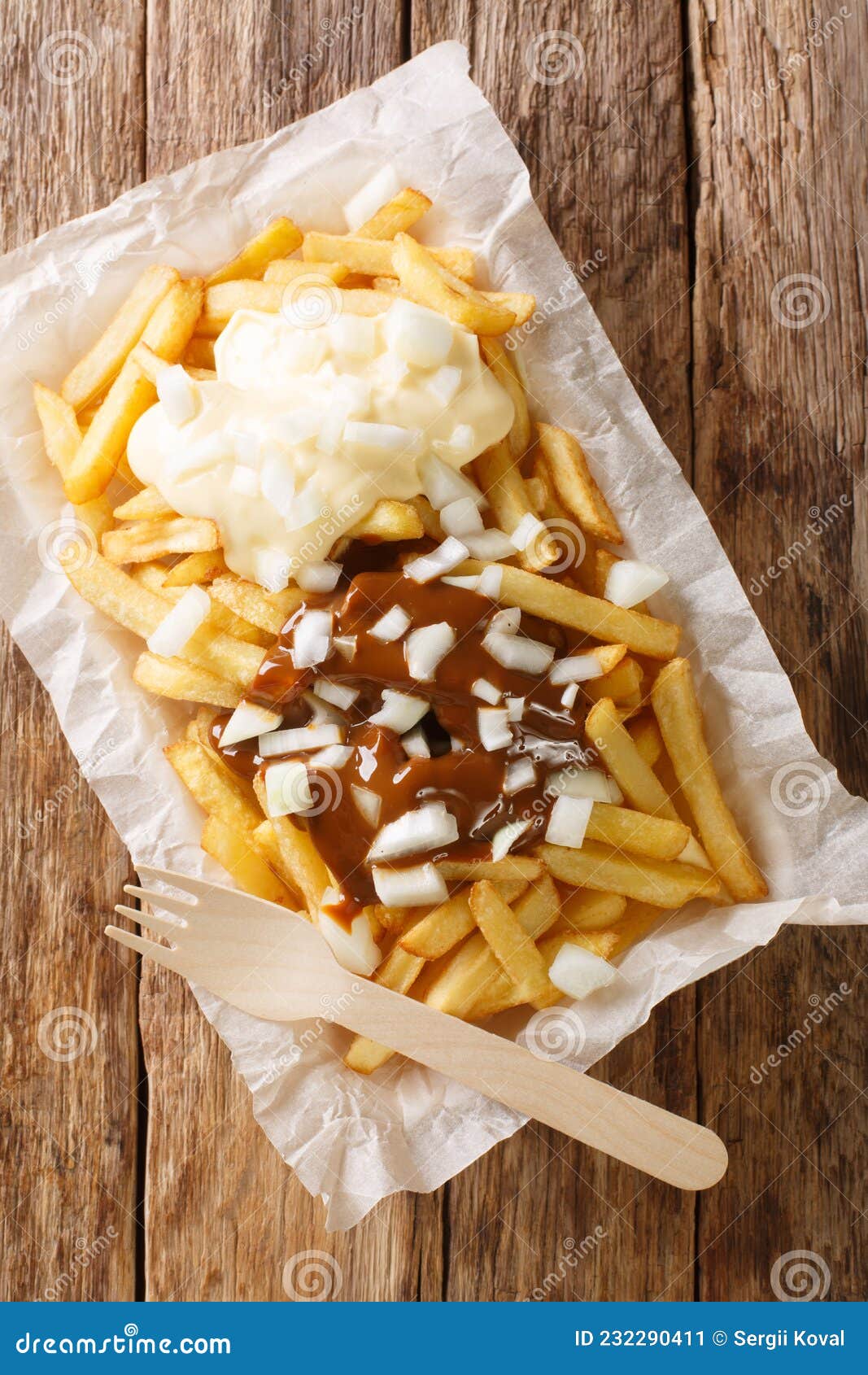 patatje oorlog dutch war fries topped with mayonnaise a thick indonesian style peanut sauce, and raw onions closeup in the plate.