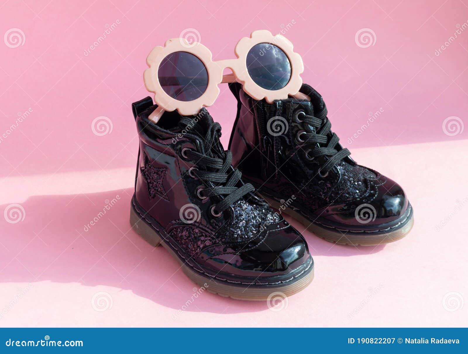 patent children`s boots shoes and accessories for little fashionistas on a pink background