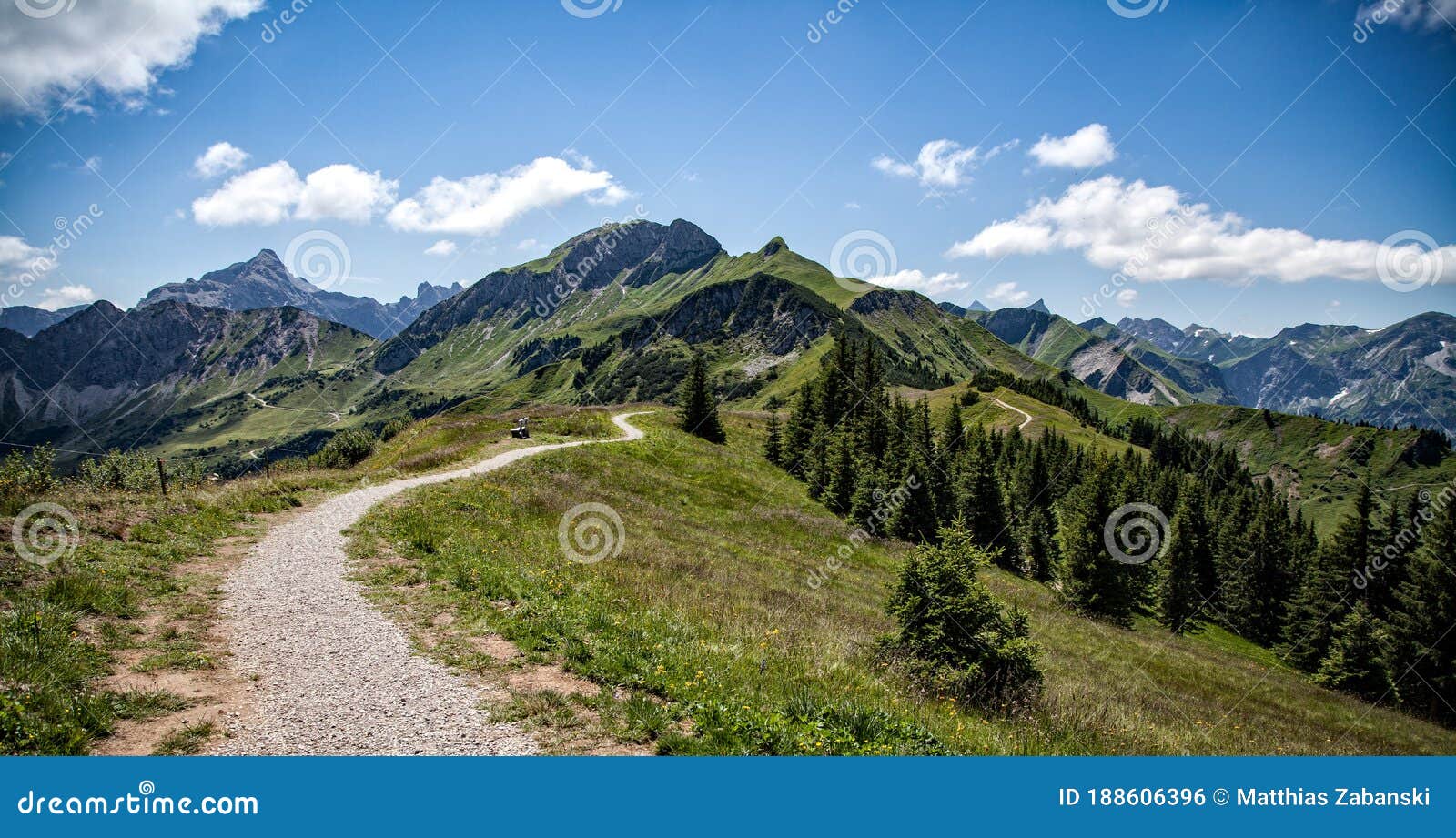 path leads into the distance with a bench to the mountain peaks in the tannheim valley in austria
