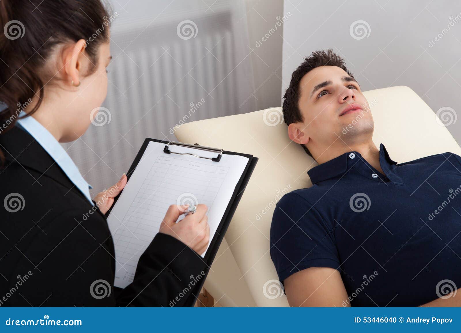 Patient Lying on Bed while Psychologist Writing Notes Stock Photo