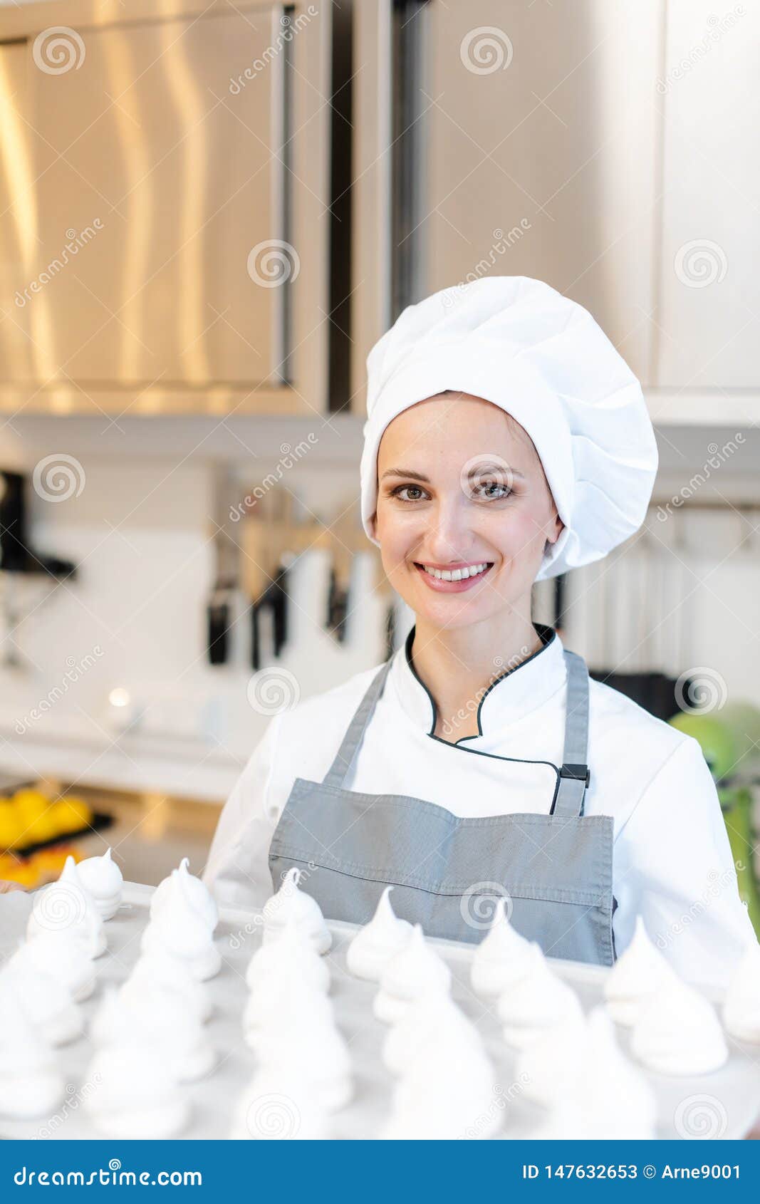 patissier in her bakery shop with lots of meringue