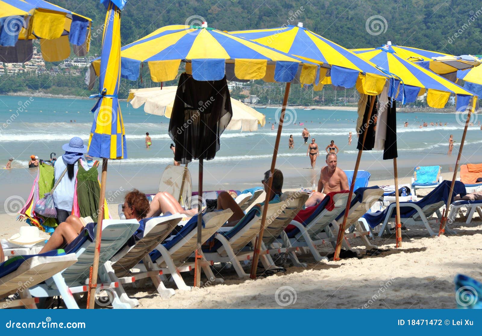 Patong, Thailand: Het Strand van Patong. Een rij van blauwe en gele paraplu's veroorlooft zich schaduw van de intense zon aan strand-goers genietend van een dag door het azuurblauwe overzees bij Strand Patong op Phuket Eiland, Thailand.