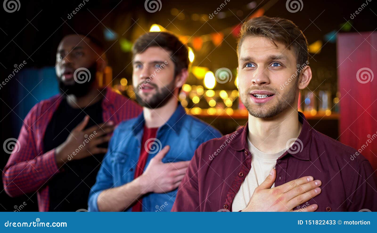 Patriotic football fans listening to national anthem, watching game in bar, stock photo