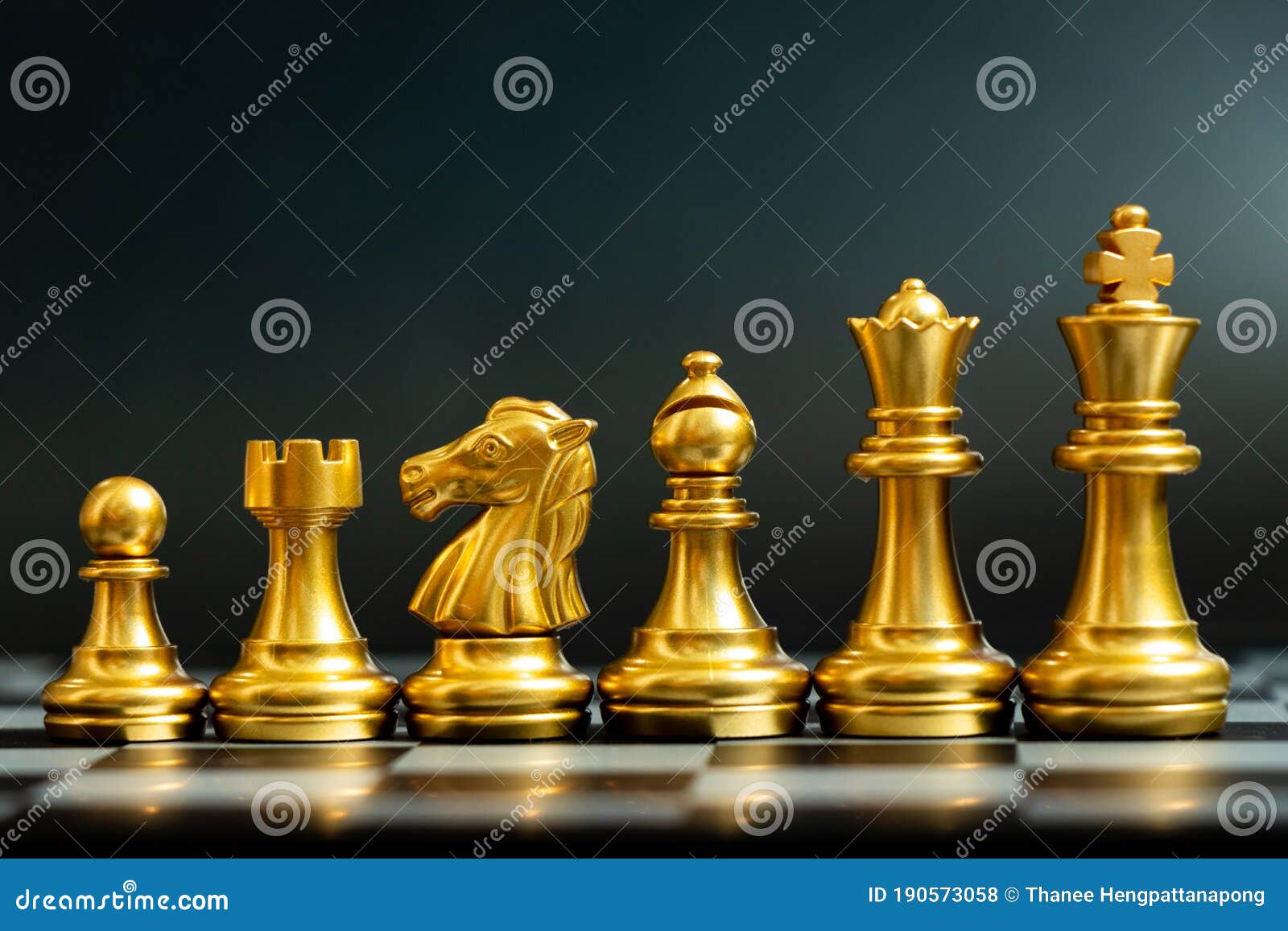 A peça de xadrez da rainha dourada em pé com o cavaleiro de prata caindo,  torre, bispo, peças de peão no tabuleiro de xadrez em fundo escuro, vista  superior. conceito de estratégia