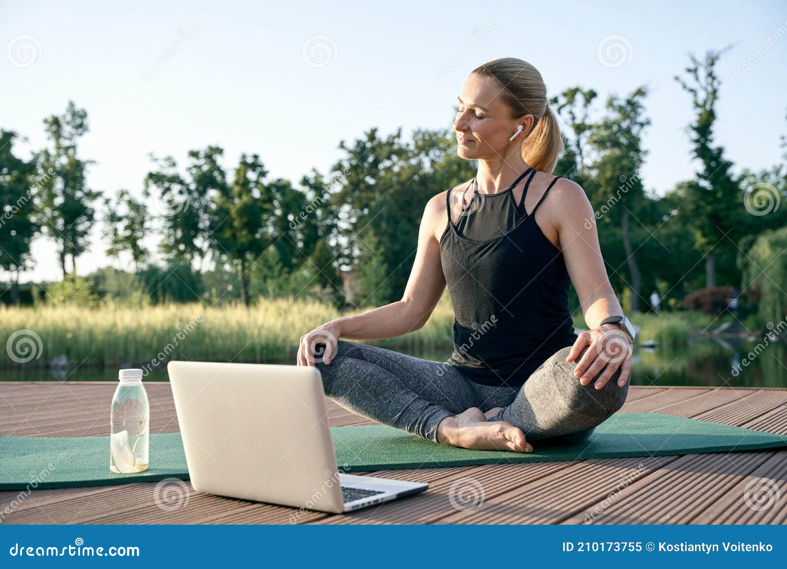 peace of mind. athletic beautiful middle aged woman watching instructional videos on a laptop while relaxing on a mat in